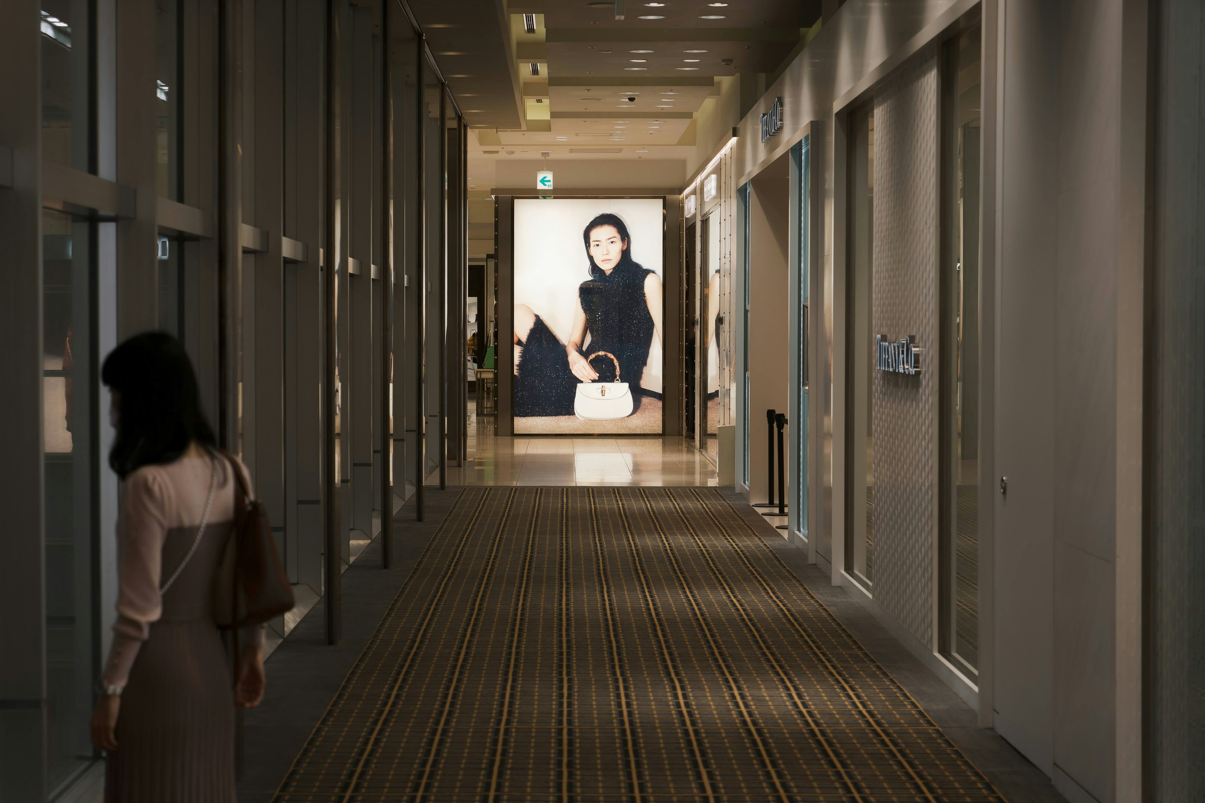 Femme marchant dans un couloir avec une grande affiche en arrière-plan