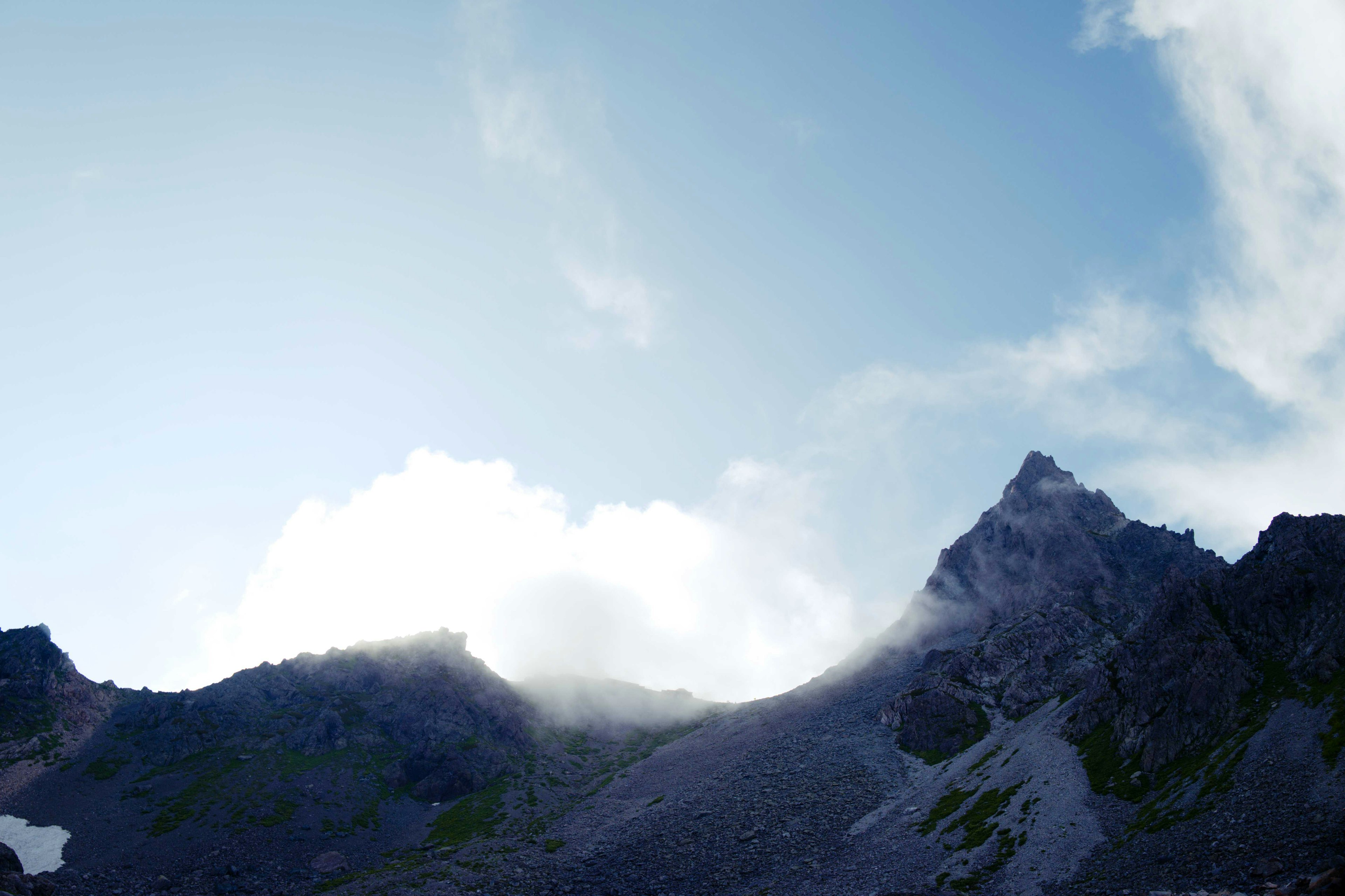 Cima de montaña bajo un cielo azul claro con nubes