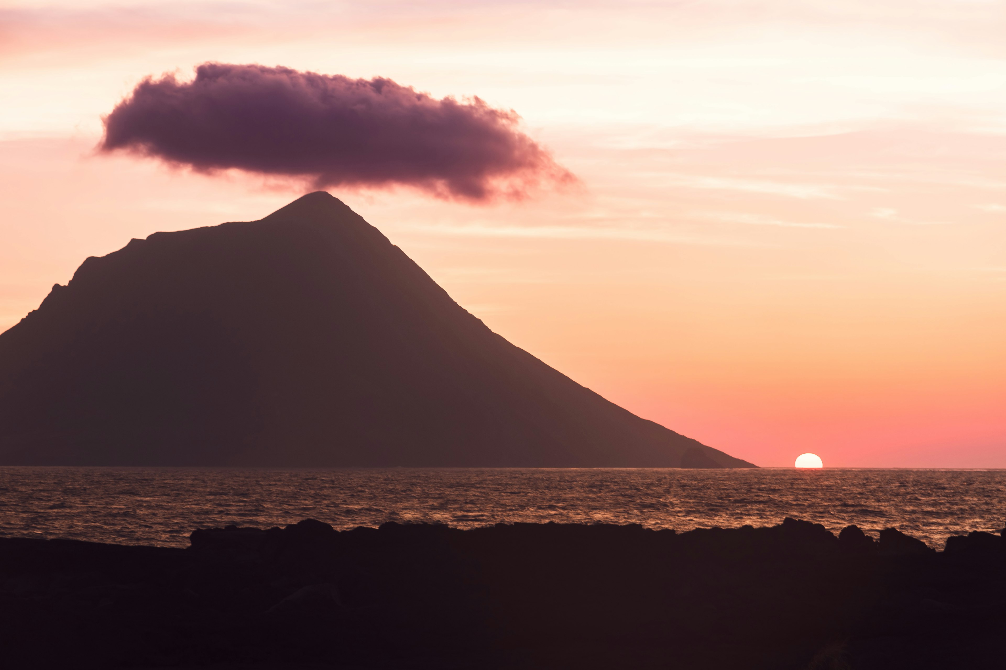 Silhouette di un vulcano contro un cielo di tramonto colorato