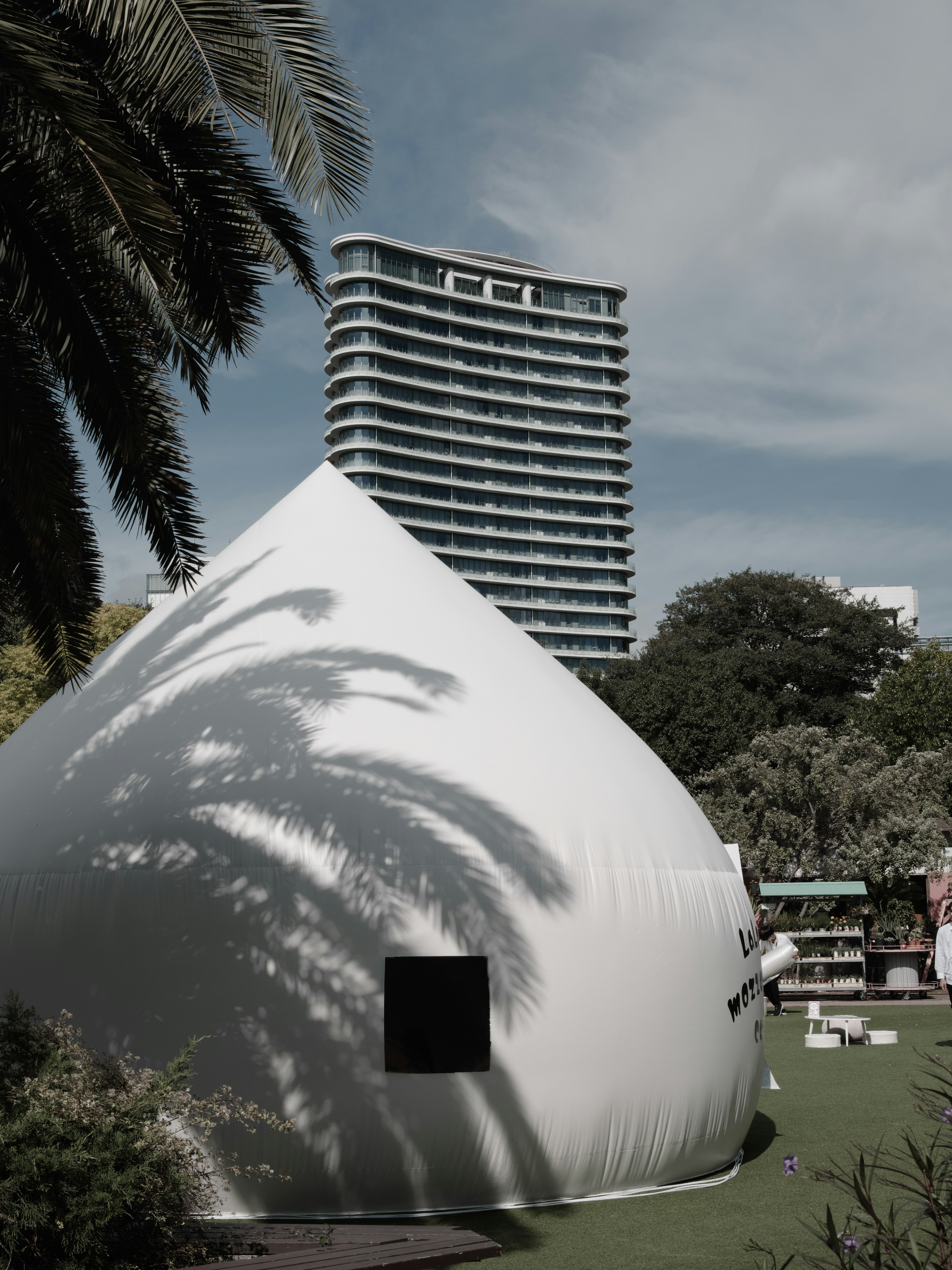 Una estructura en forma de cúpula blanca con un edificio de gran altura al fondo