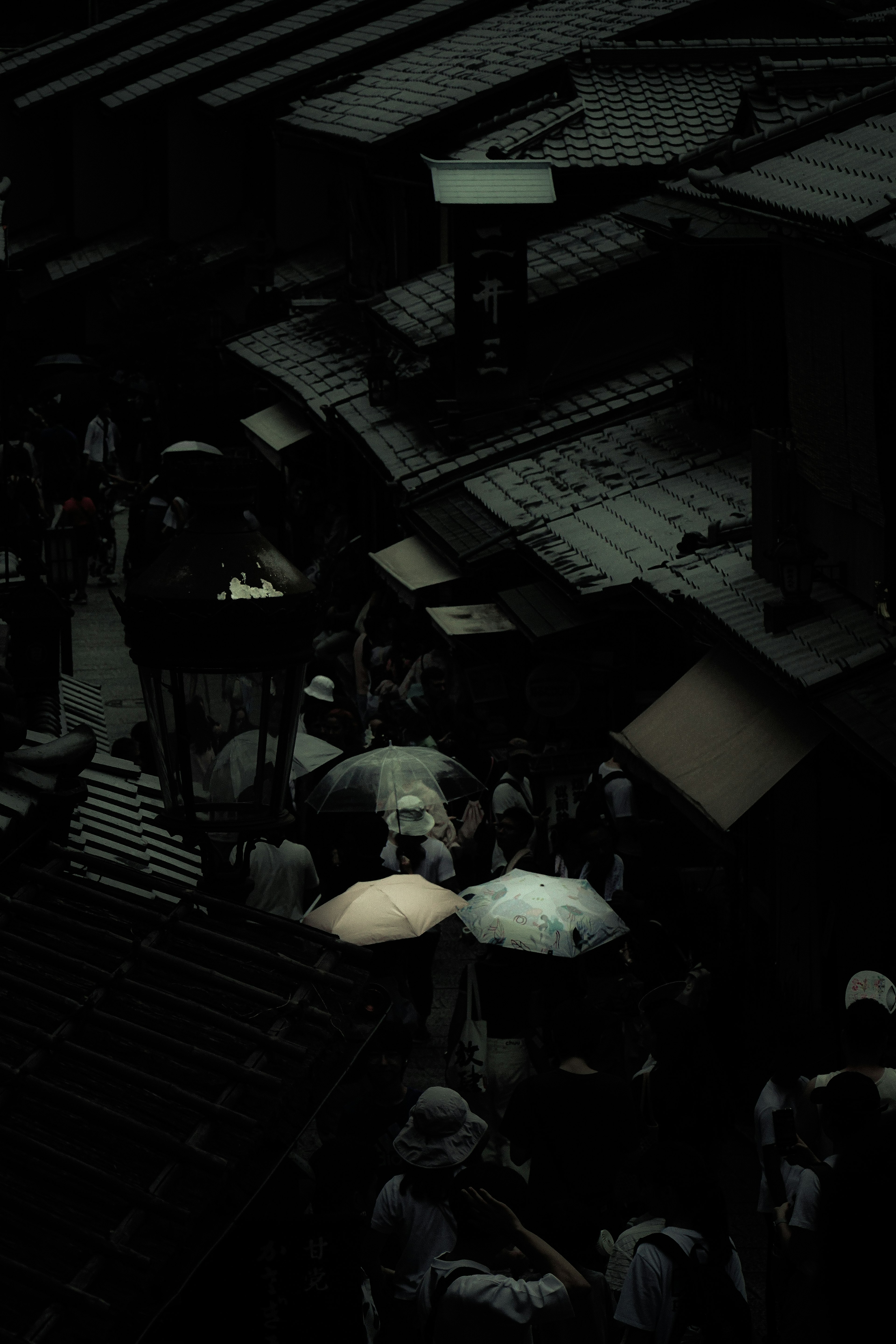 Crowd of people with umbrellas in a dark alley