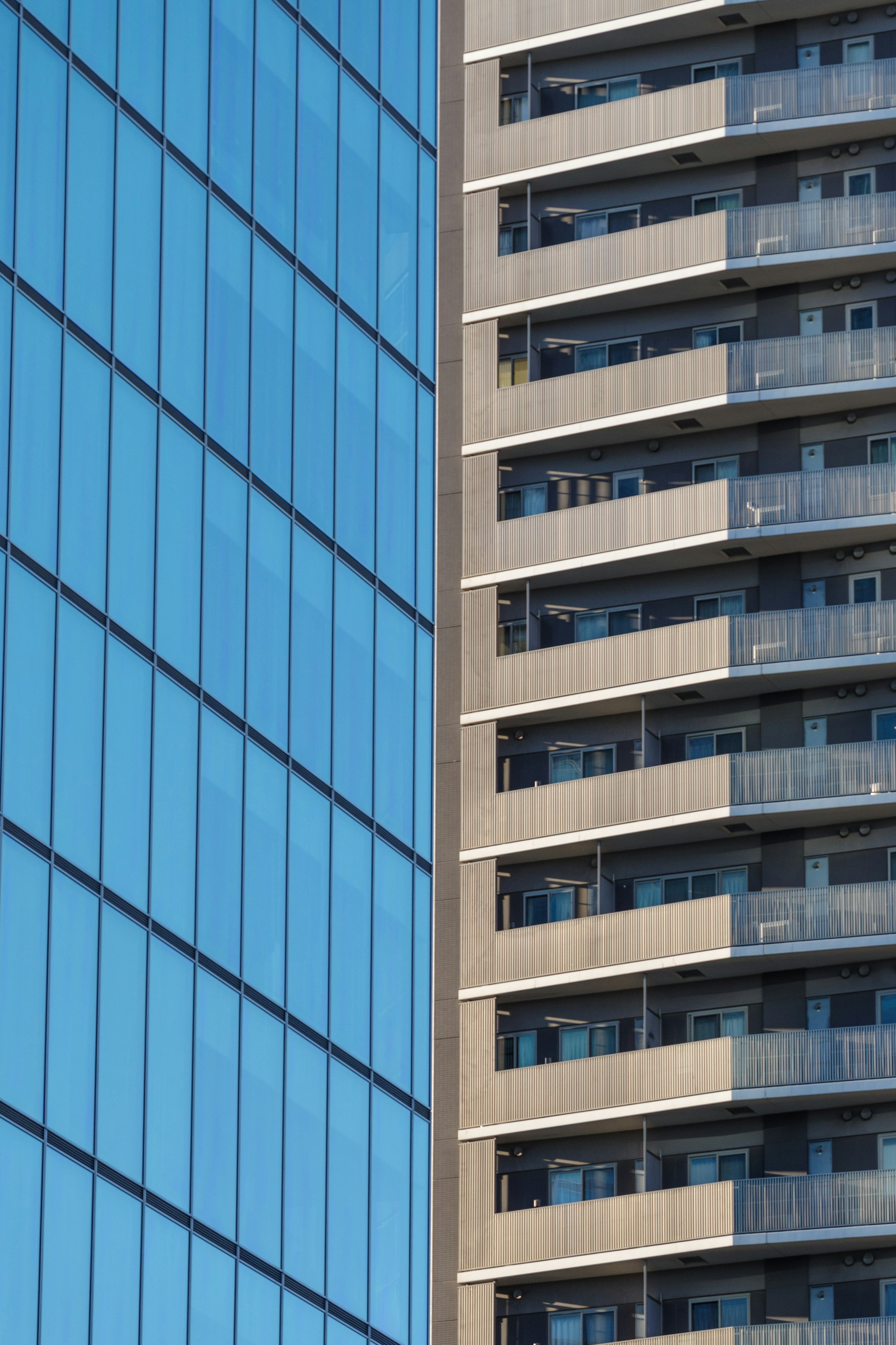 Vue latérale d'un bâtiment avec une façade en verre bleu et des balcons