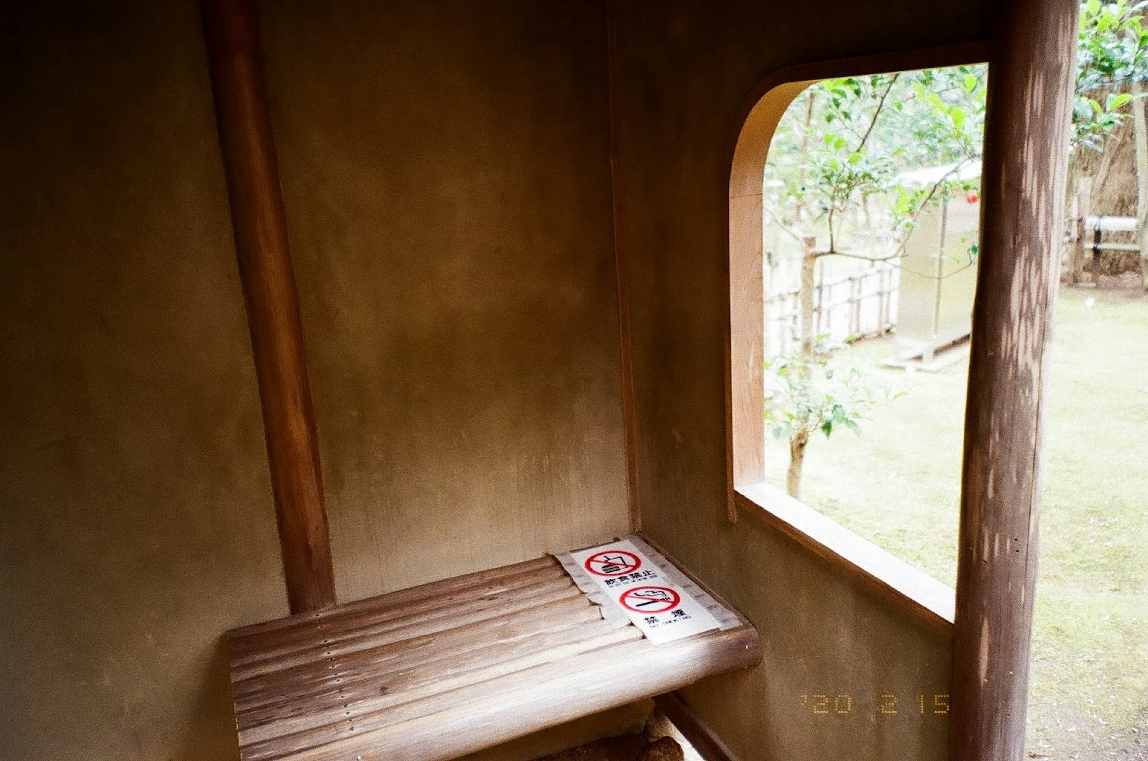 Meja kayu kecil dengan jendela bulat di ruangan dinding tanah