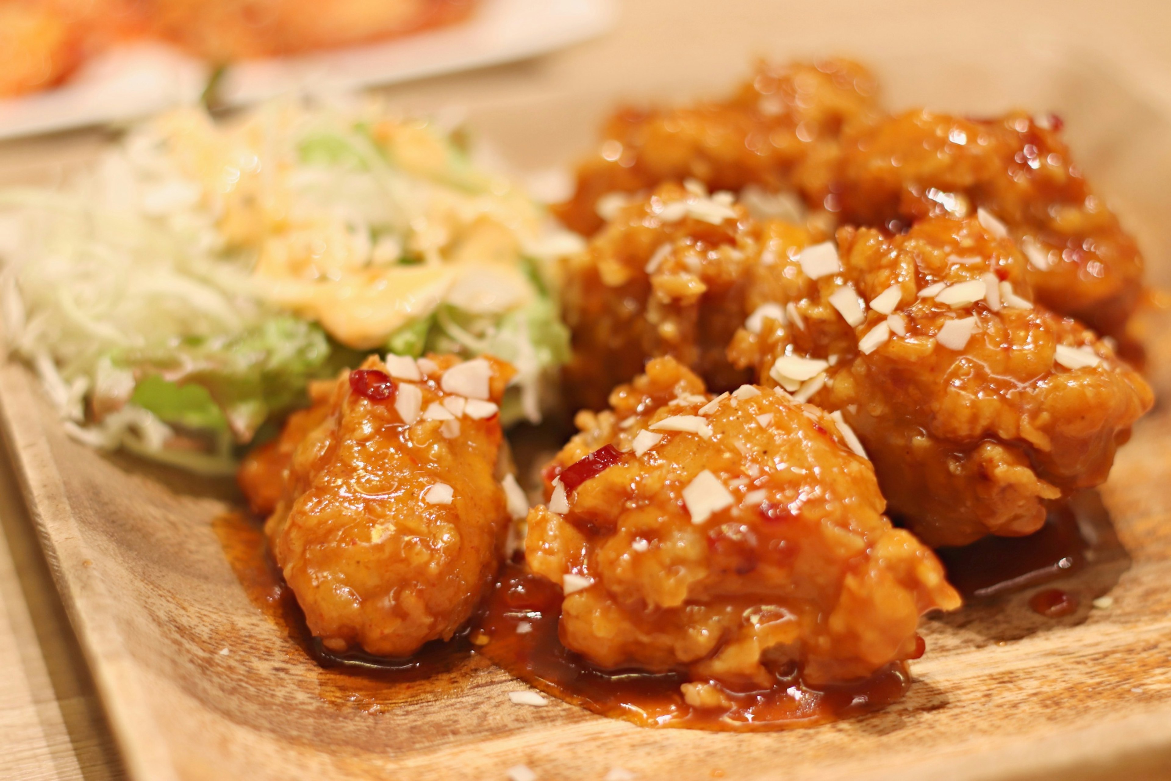 Plato de pollo frito crujiente cubierto con salsa dulce y picante decorado con cebollitas picadas