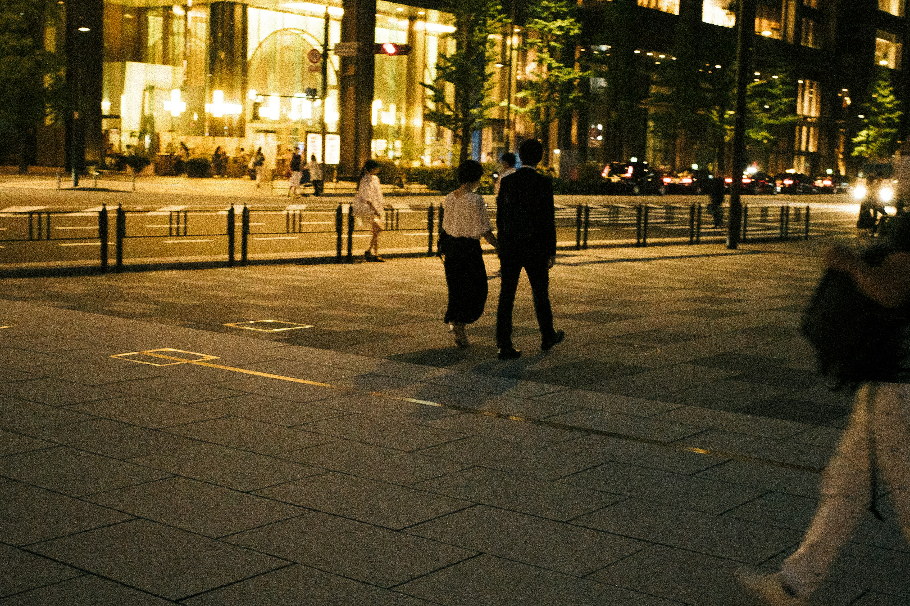 夜の街を歩くカップルと明るい建物の背景