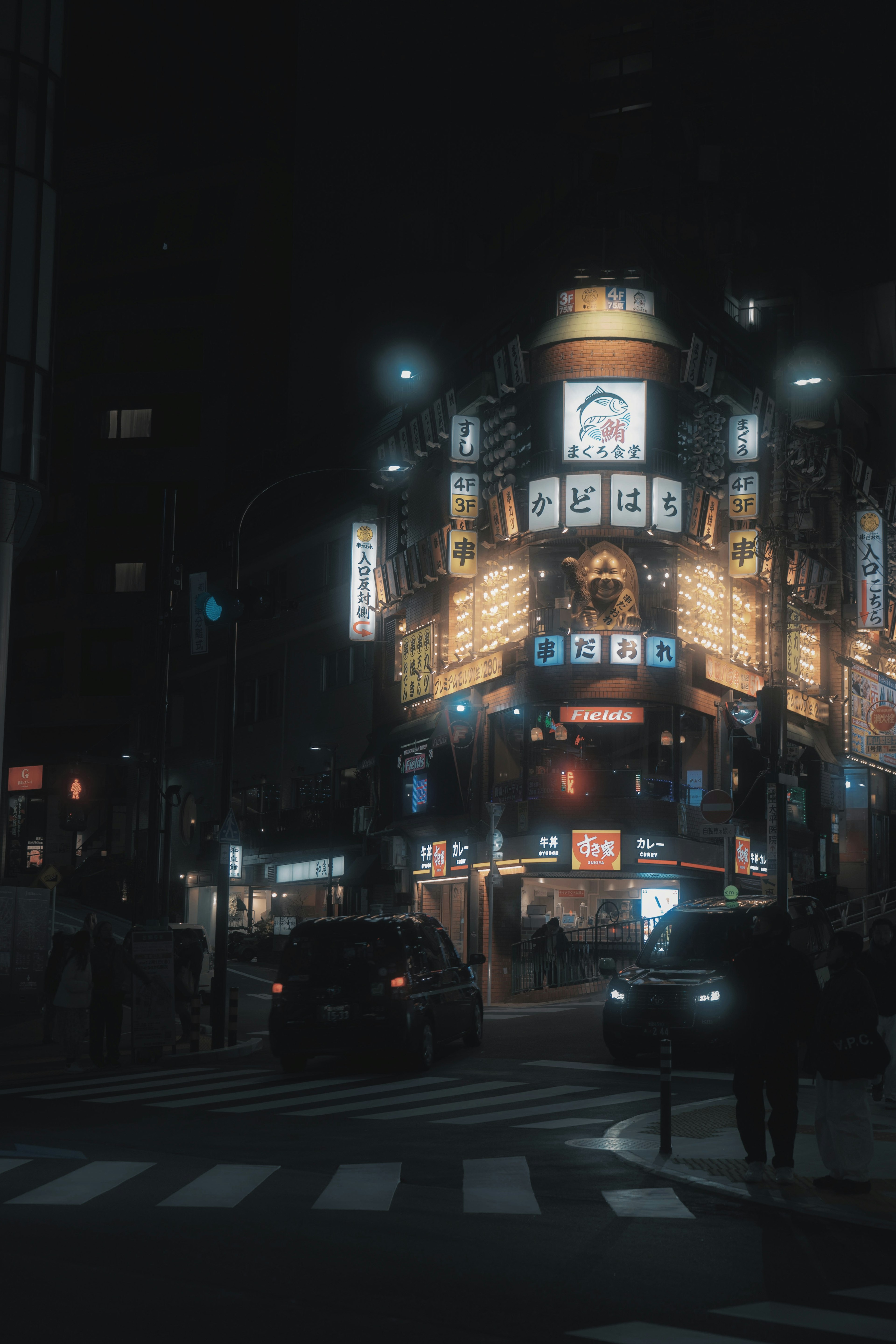 Night cityscape with glowing neon signs and cars at a busy intersection