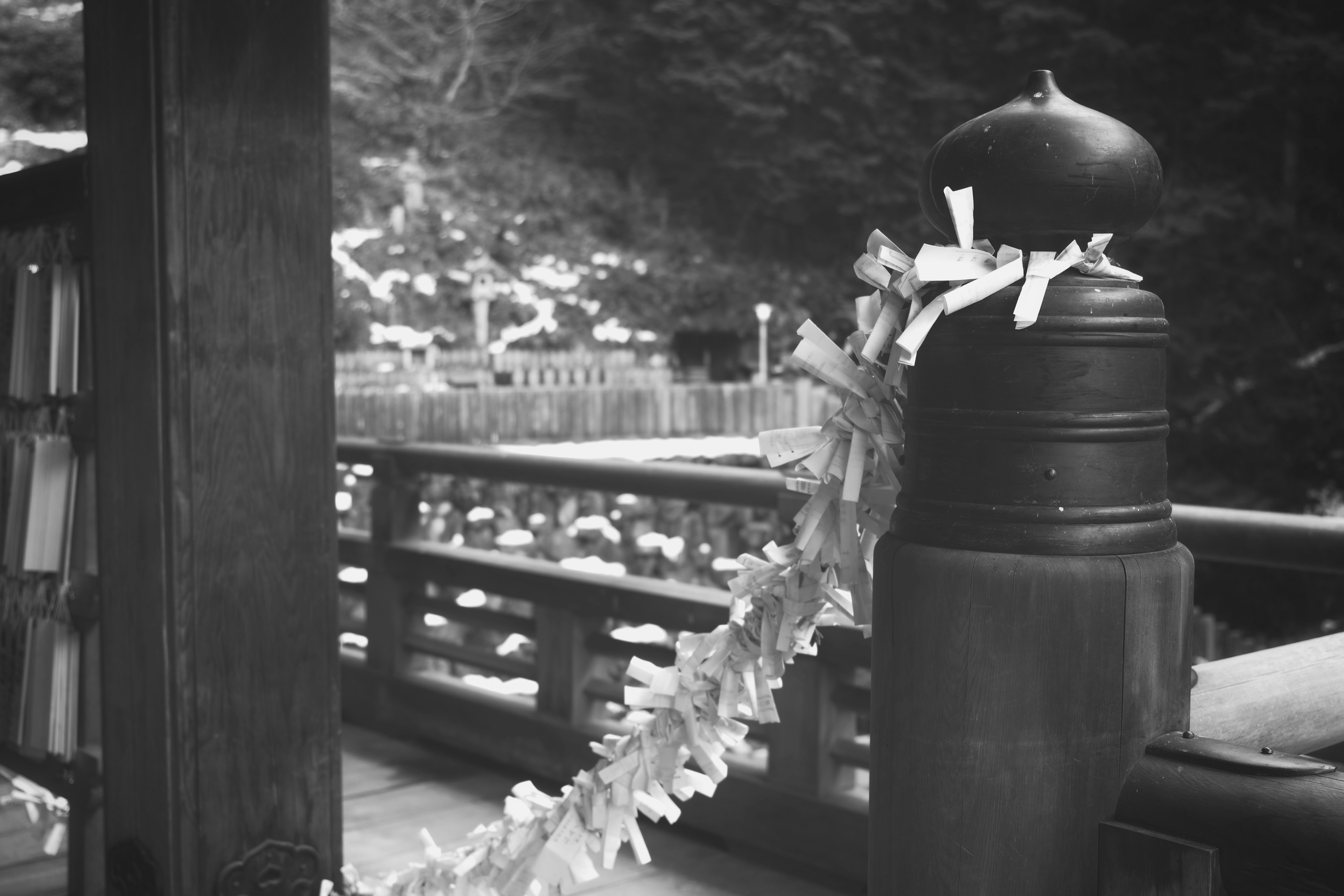 Image en noir et blanc d'un poteau décoré sur un pont avec un arrière-plan naturel