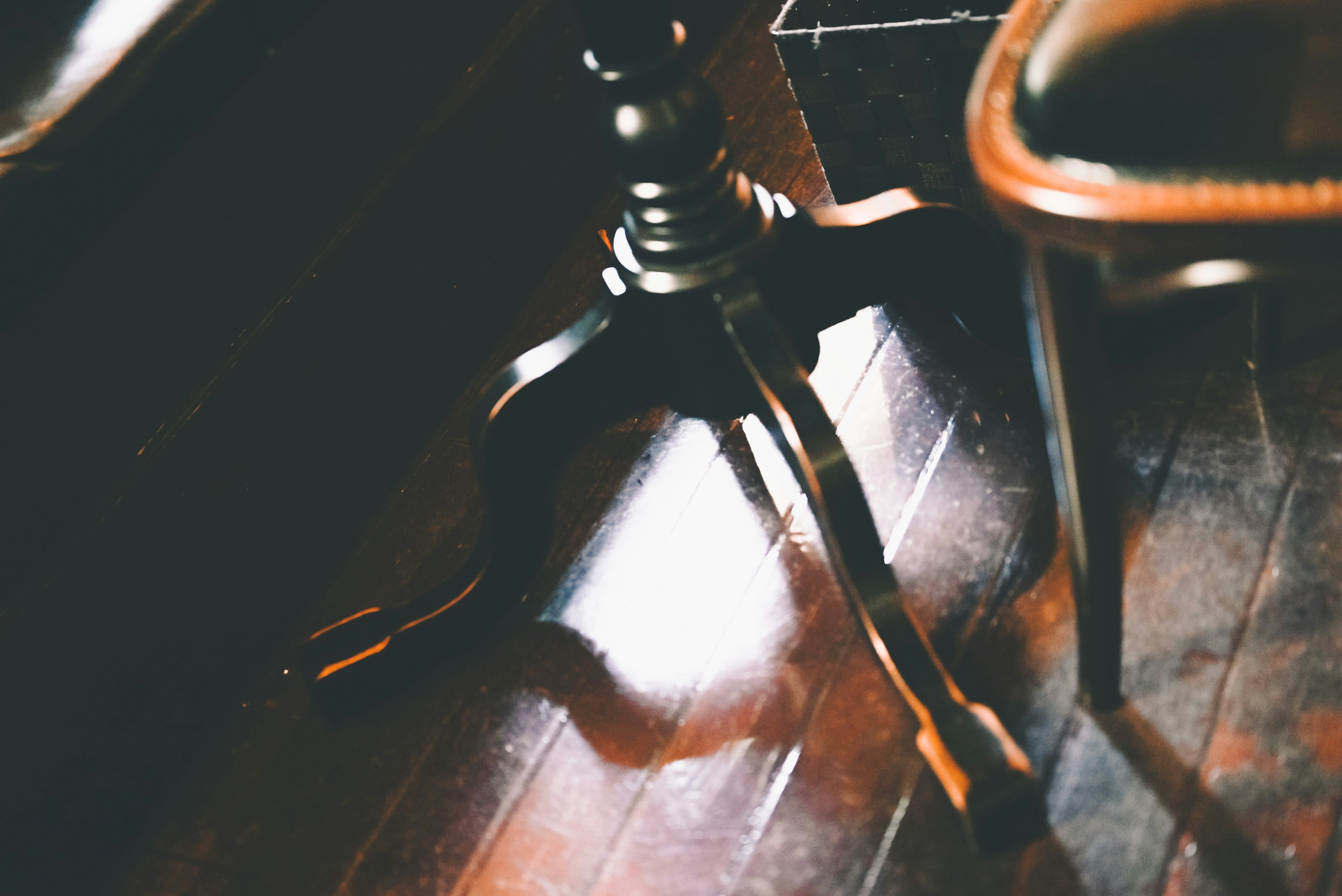 Image of a table leg and part of a chair on a dark wooden floor