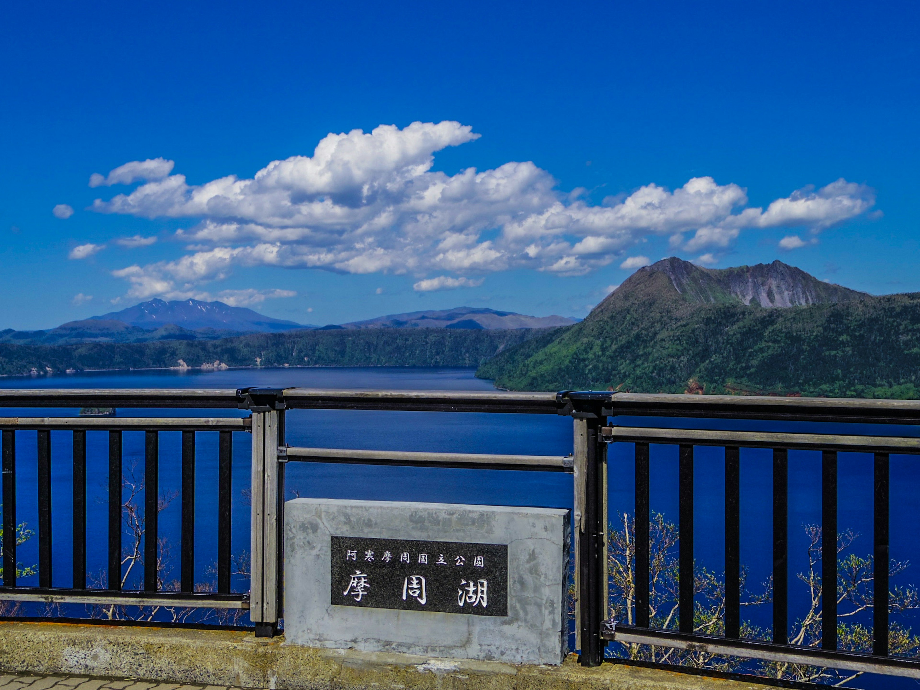 Scenic view of a lake and mountains under a blue sky with white clouds