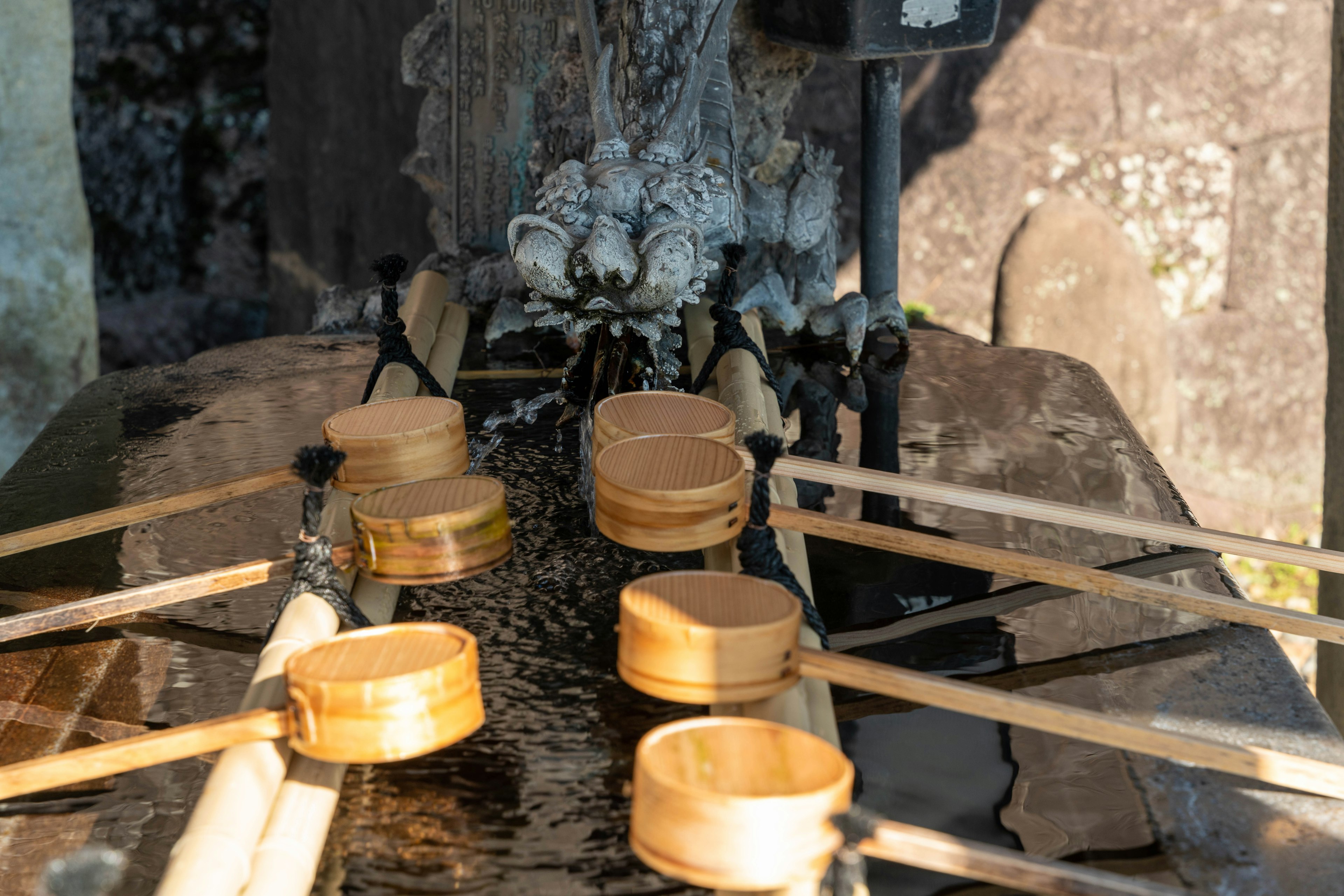 Cuillères en bois disposées à la fontaine de purification d'un sanctuaire