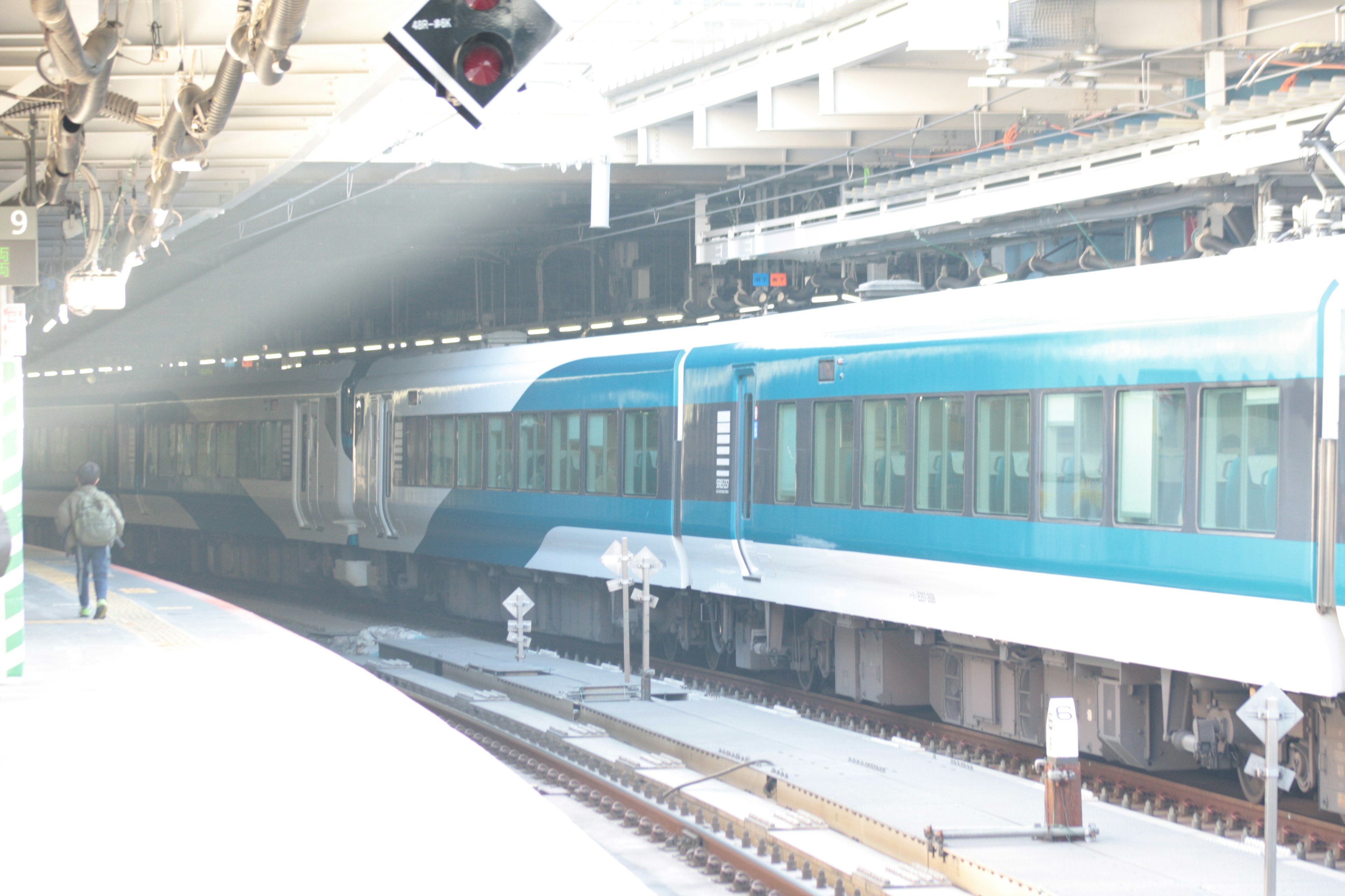 Kereta biru di platform stasiun dengan lampu sinyal di atas