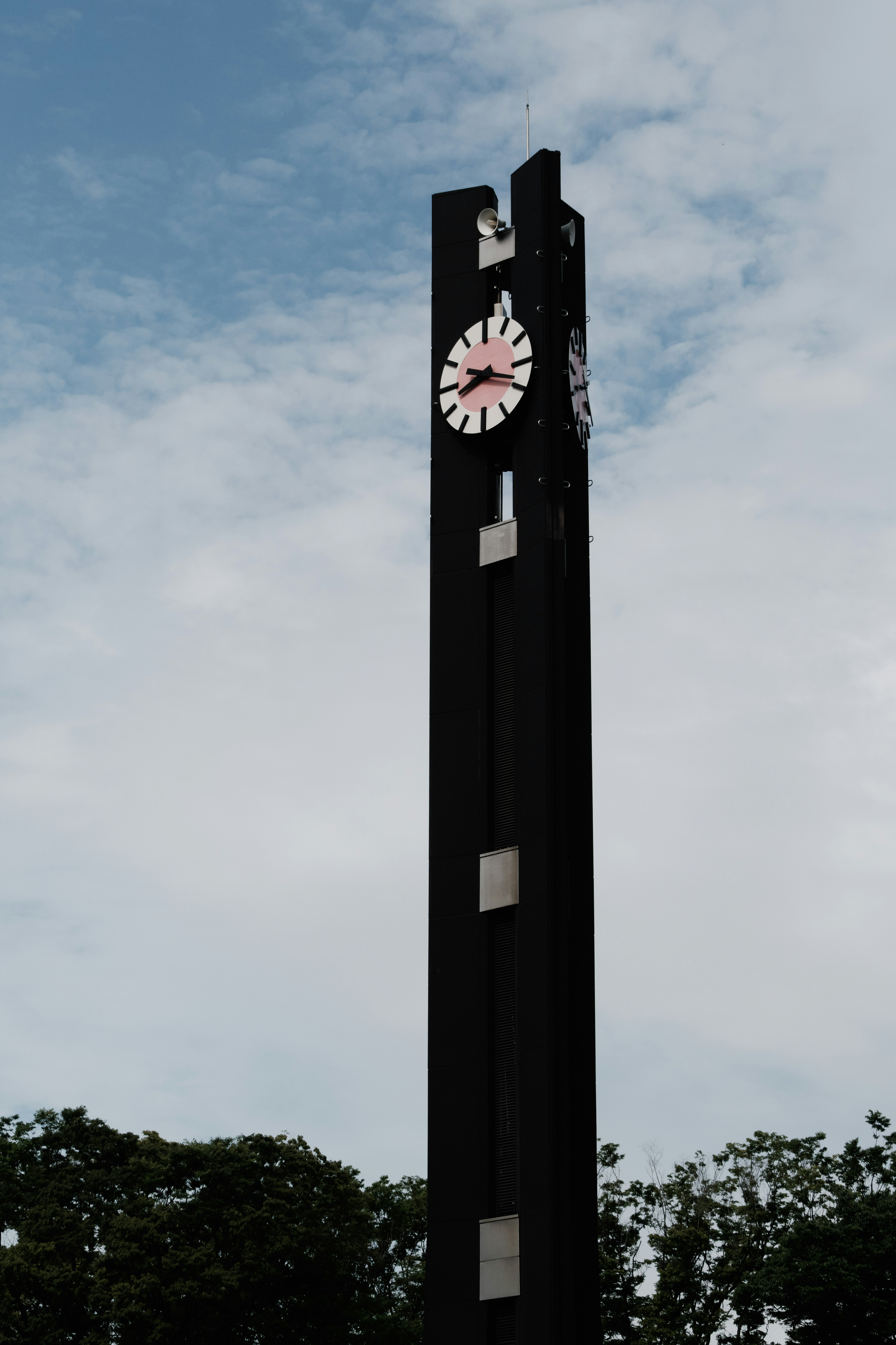 Tall black clock tower featuring a red clock and modern design