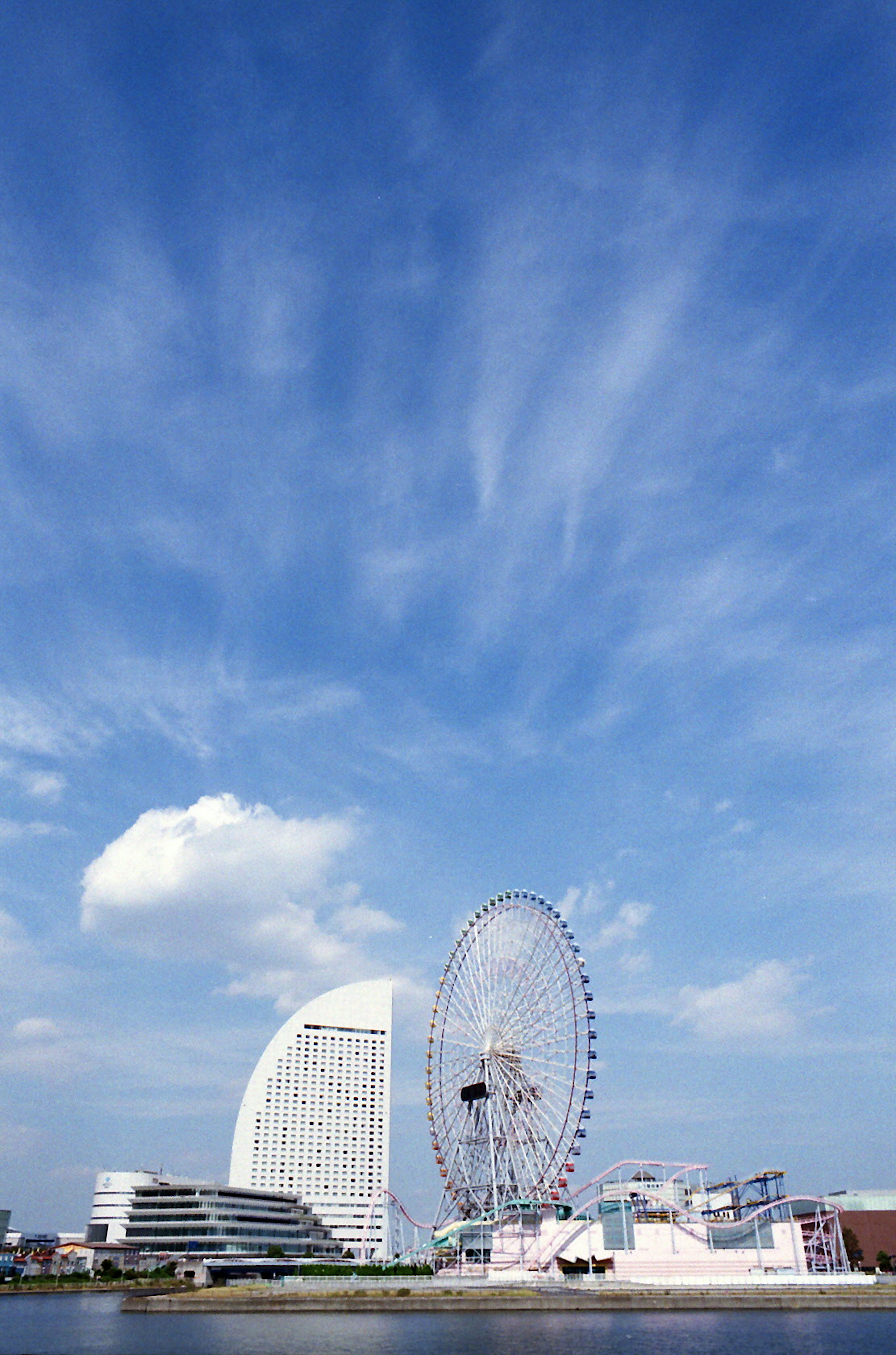 Grande roue et bâtiment moderne sous un ciel bleu avec des nuages blancs