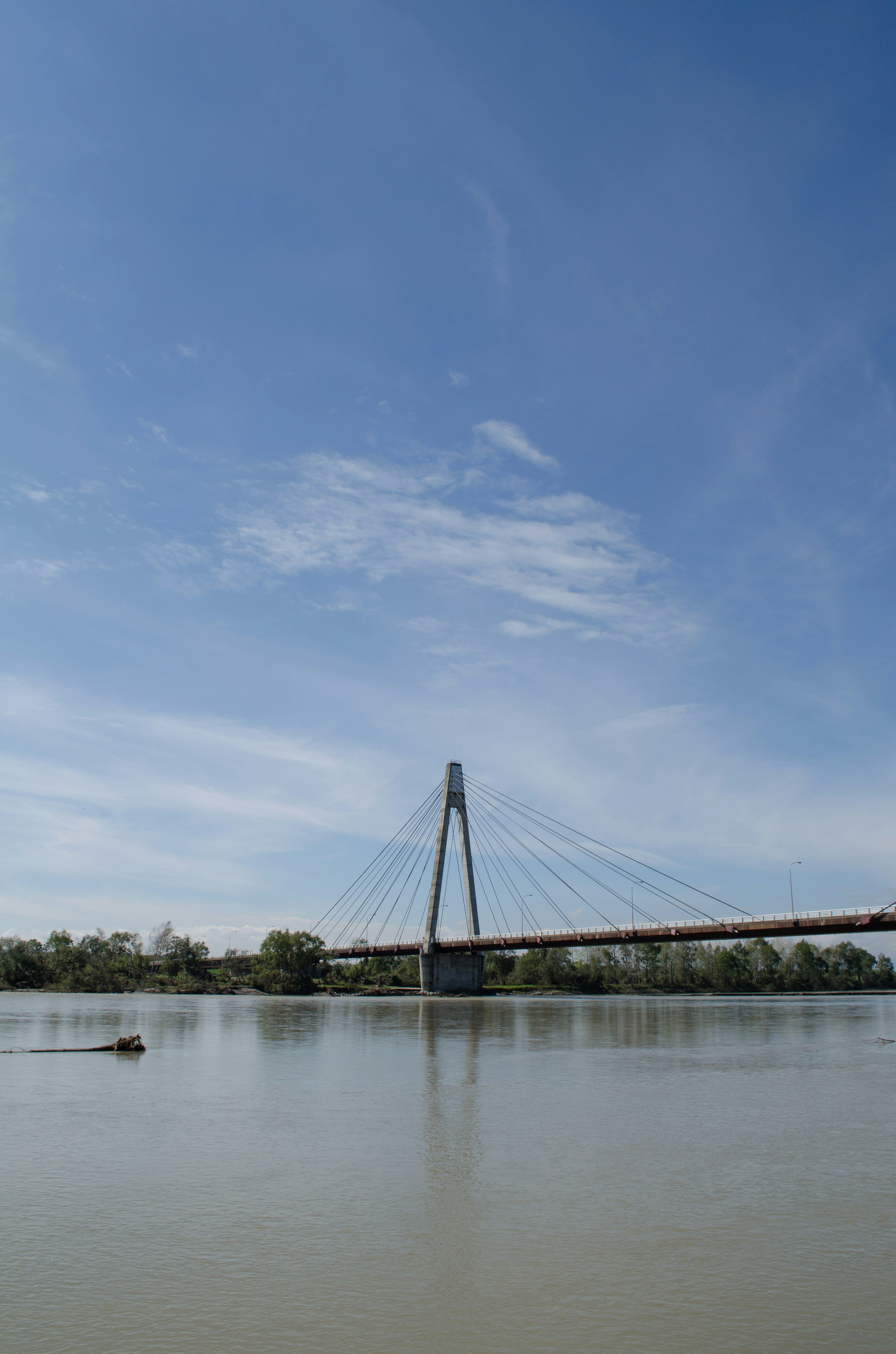 Hängebrücke über einen ruhigen Fluss unter einem klaren blauen Himmel