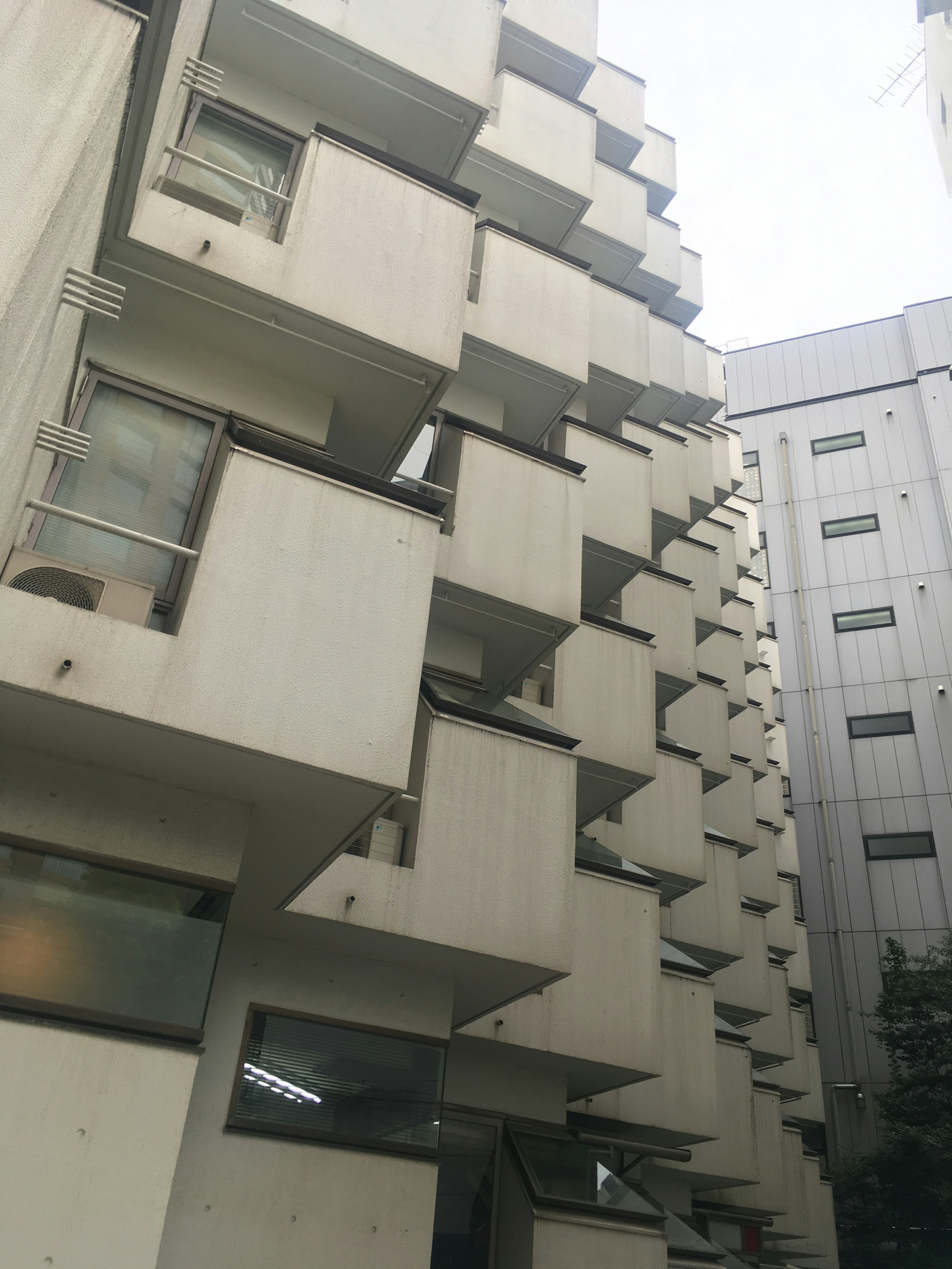 Bangunan apartemen beton unik dengan balkon khas dan arsitektur modern