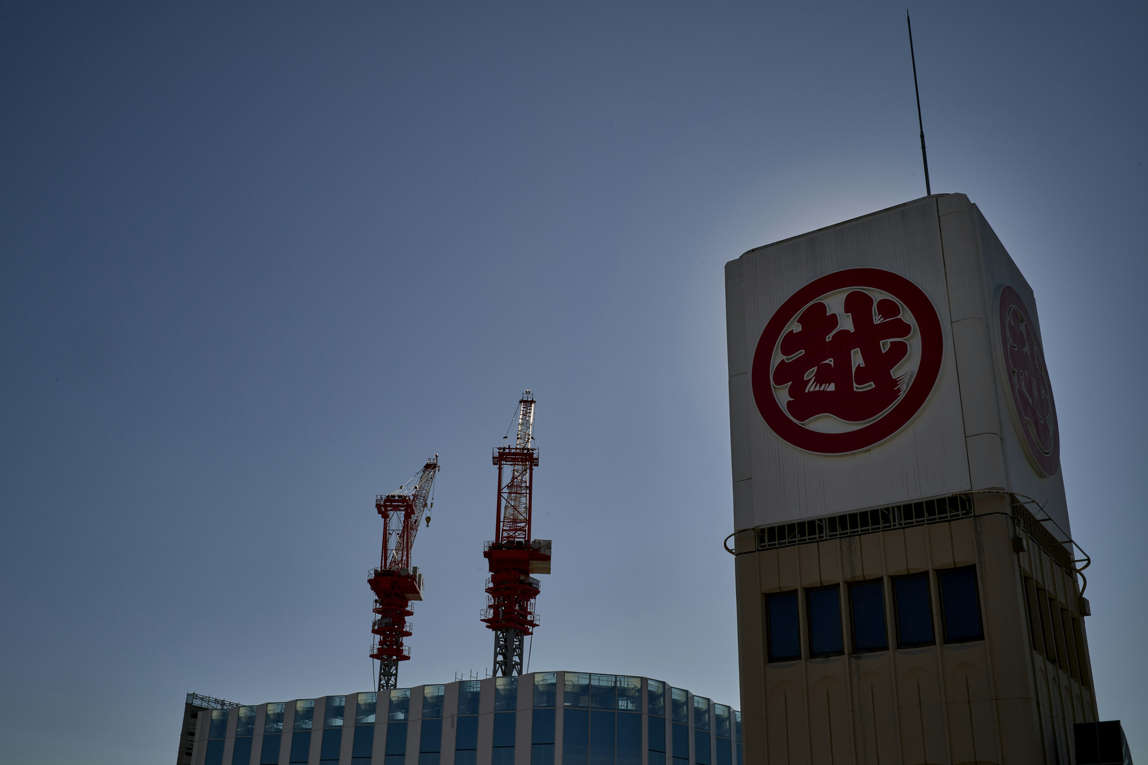 Großes Gebäude unter blauem Himmel mit Turm mit rotem Logo