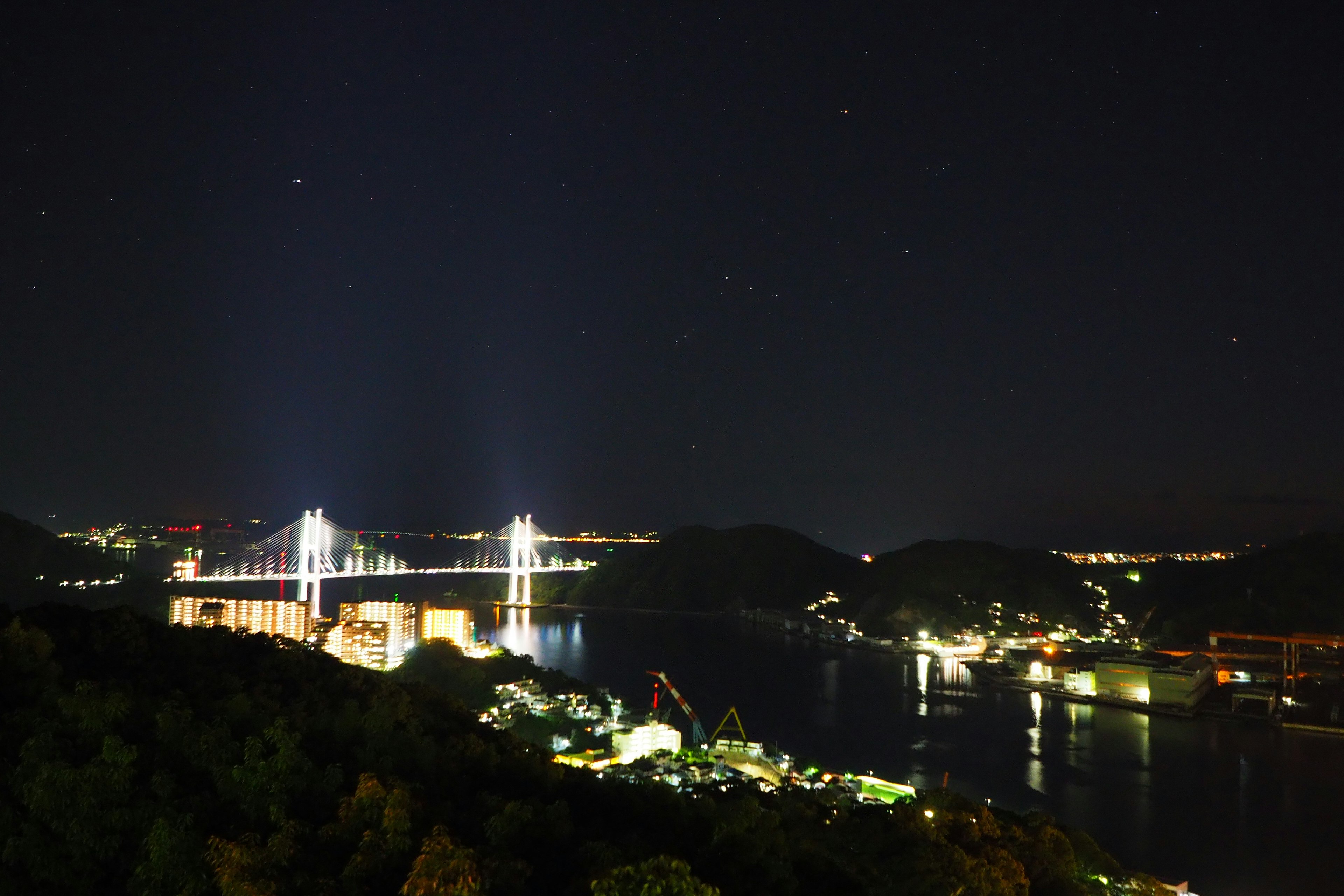 Vista nocturna de un hermoso puente bajo un cielo estrellado con una zona costera