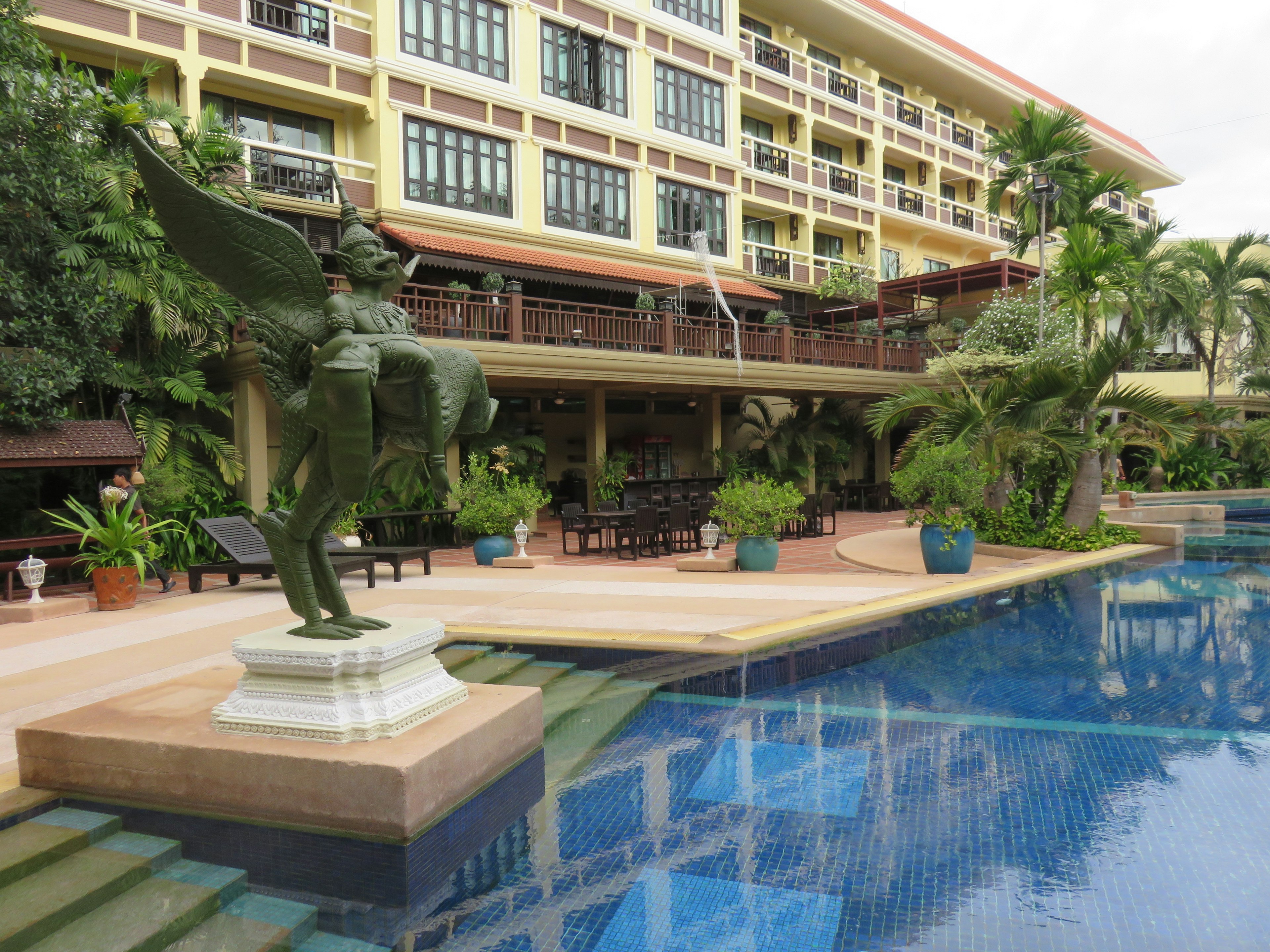 Extérieur d'un hôtel avec une belle sculpture au bord de la piscine entourée de verdure luxuriante