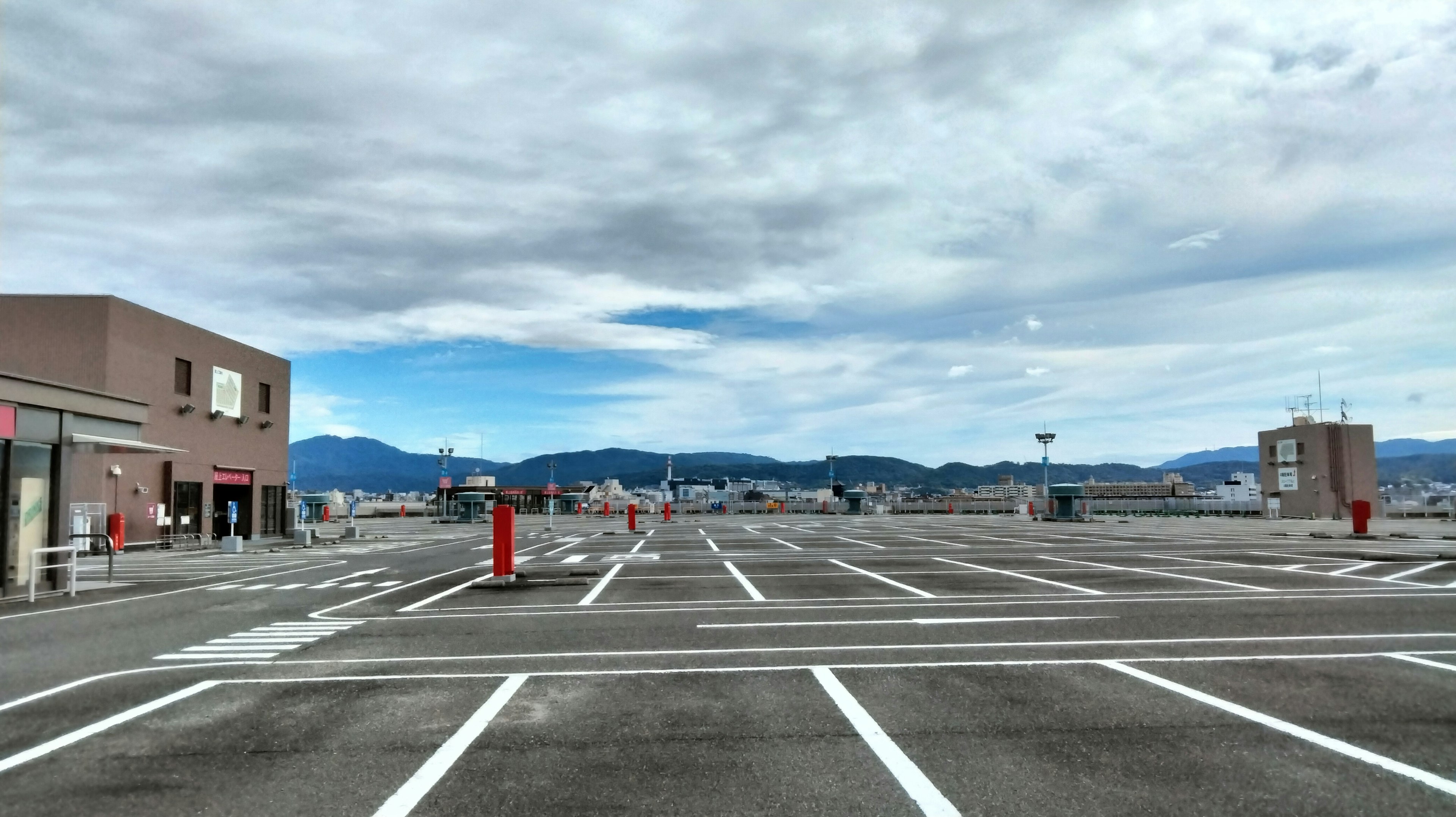 Empty parking lot with visible white lines and cloudy sky