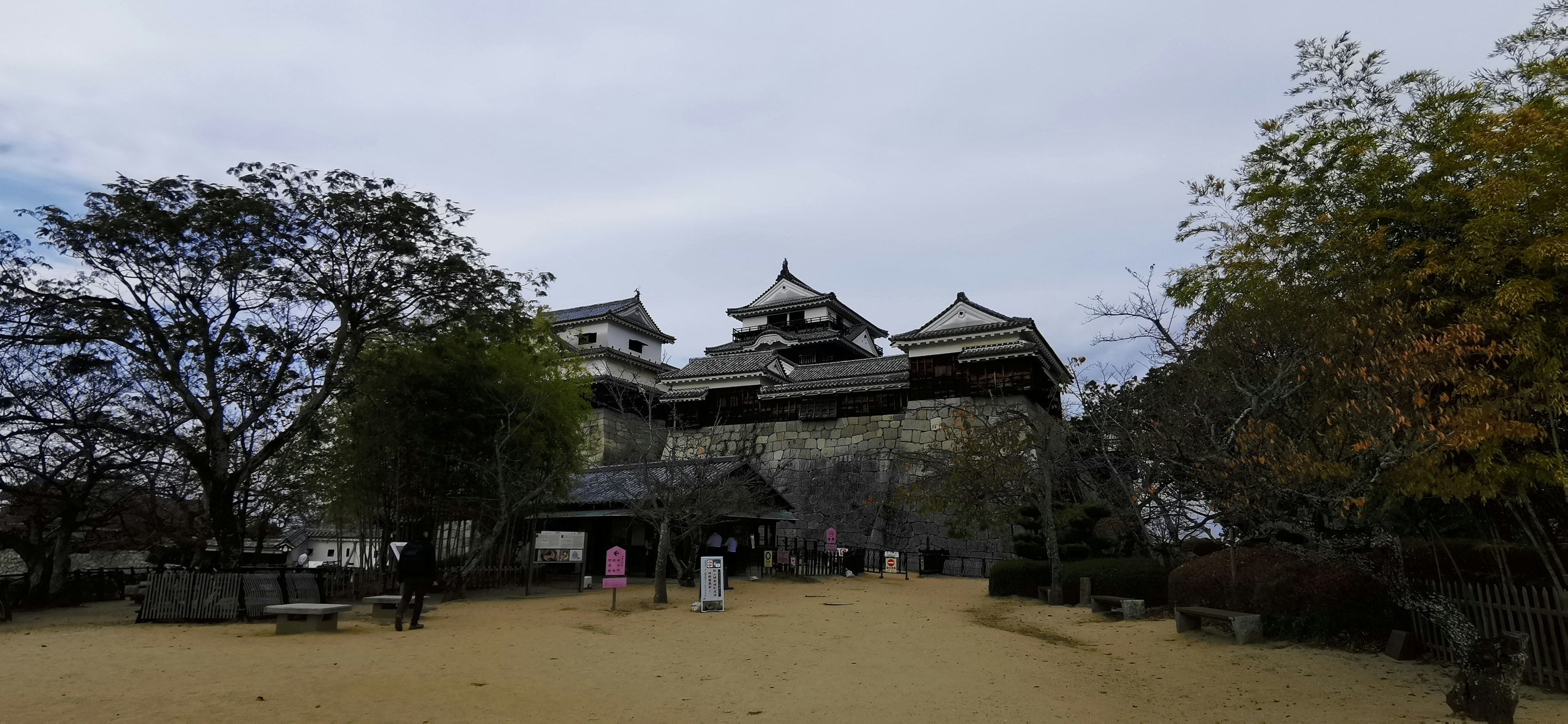 A view of a castle in a quiet park with surrounding trees and visitors