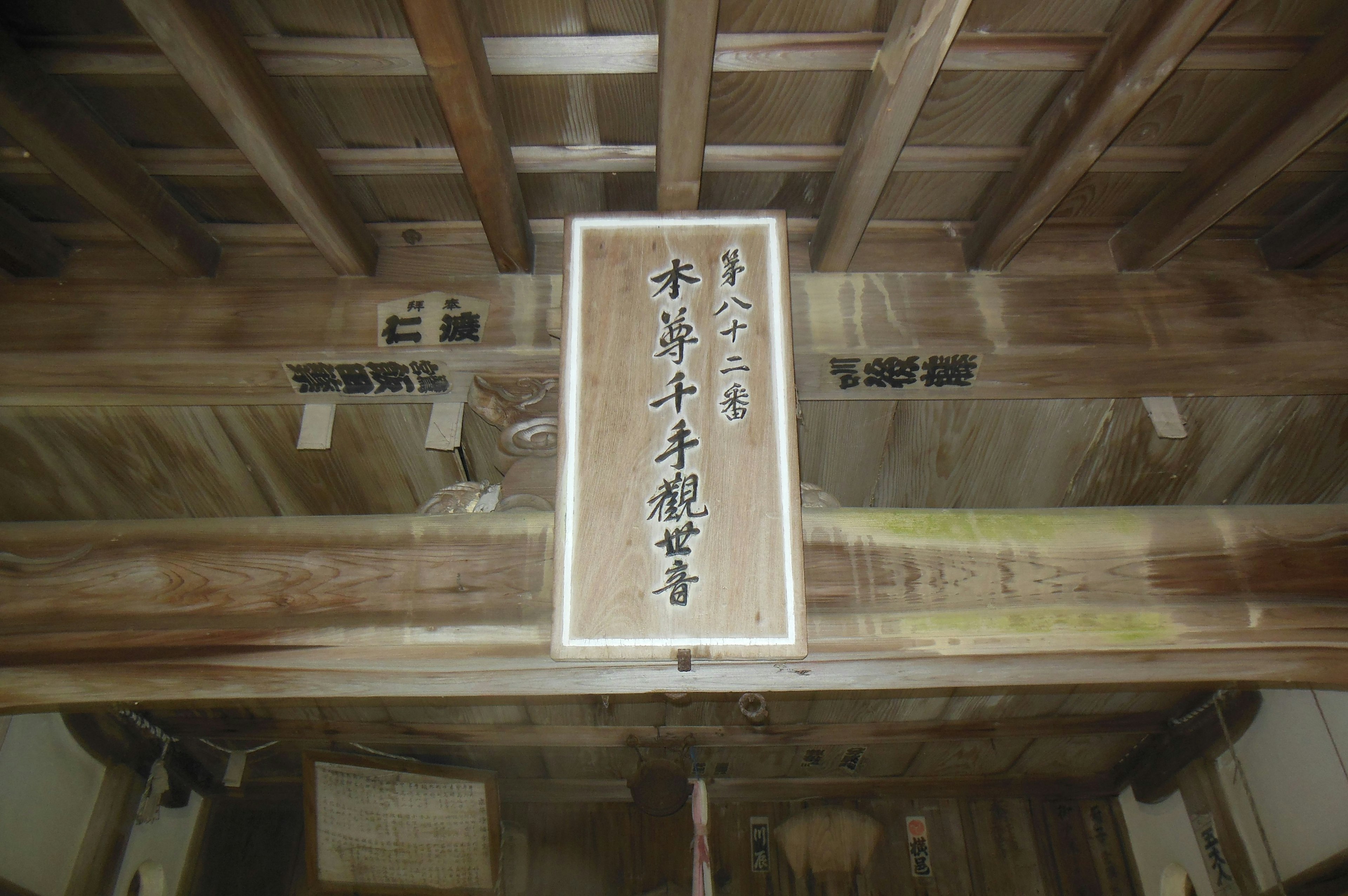 Calligraphy artwork displayed on a wooden beam indoors