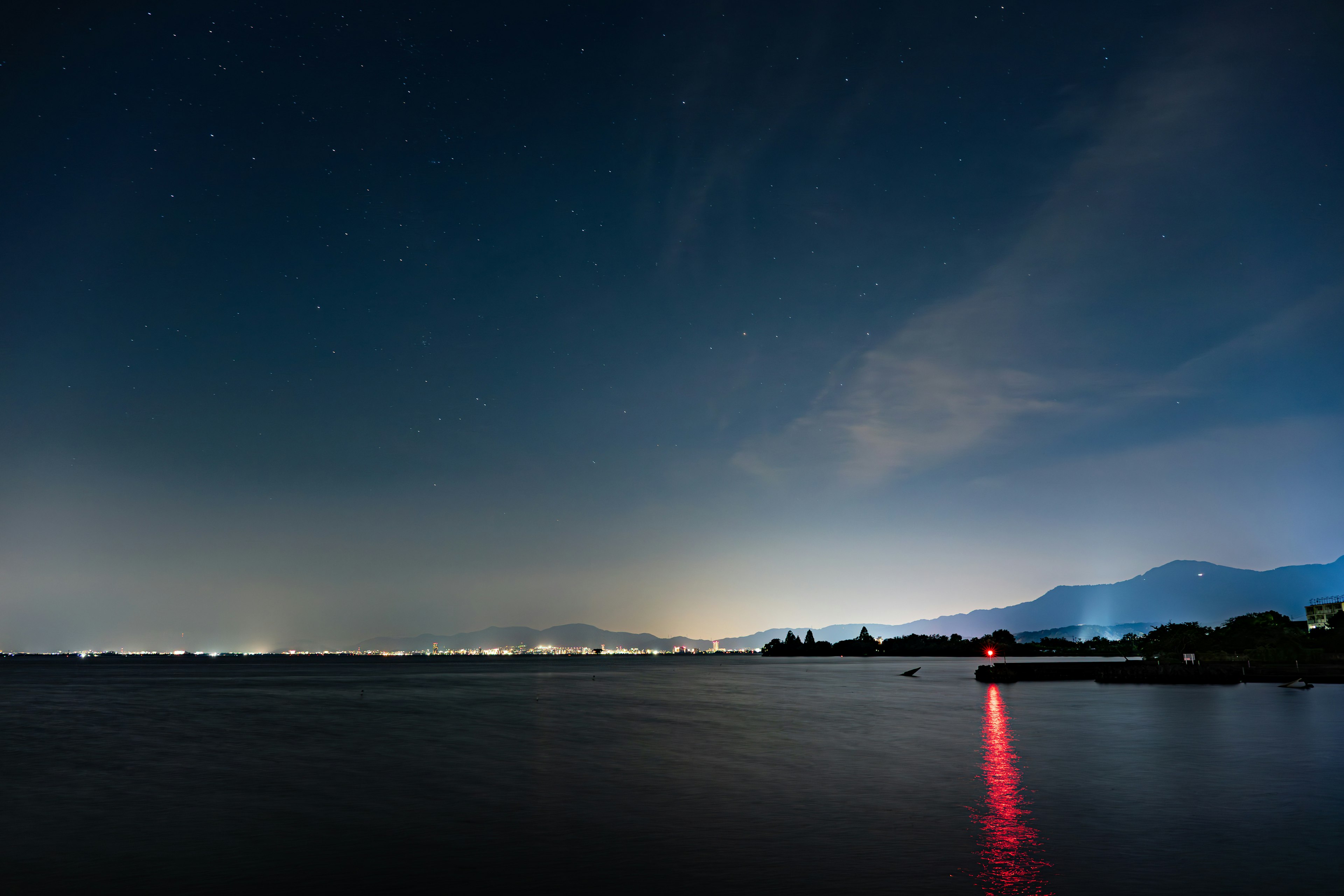Langit malam berbintang di atas danau Cahaya merah memantul di atas air