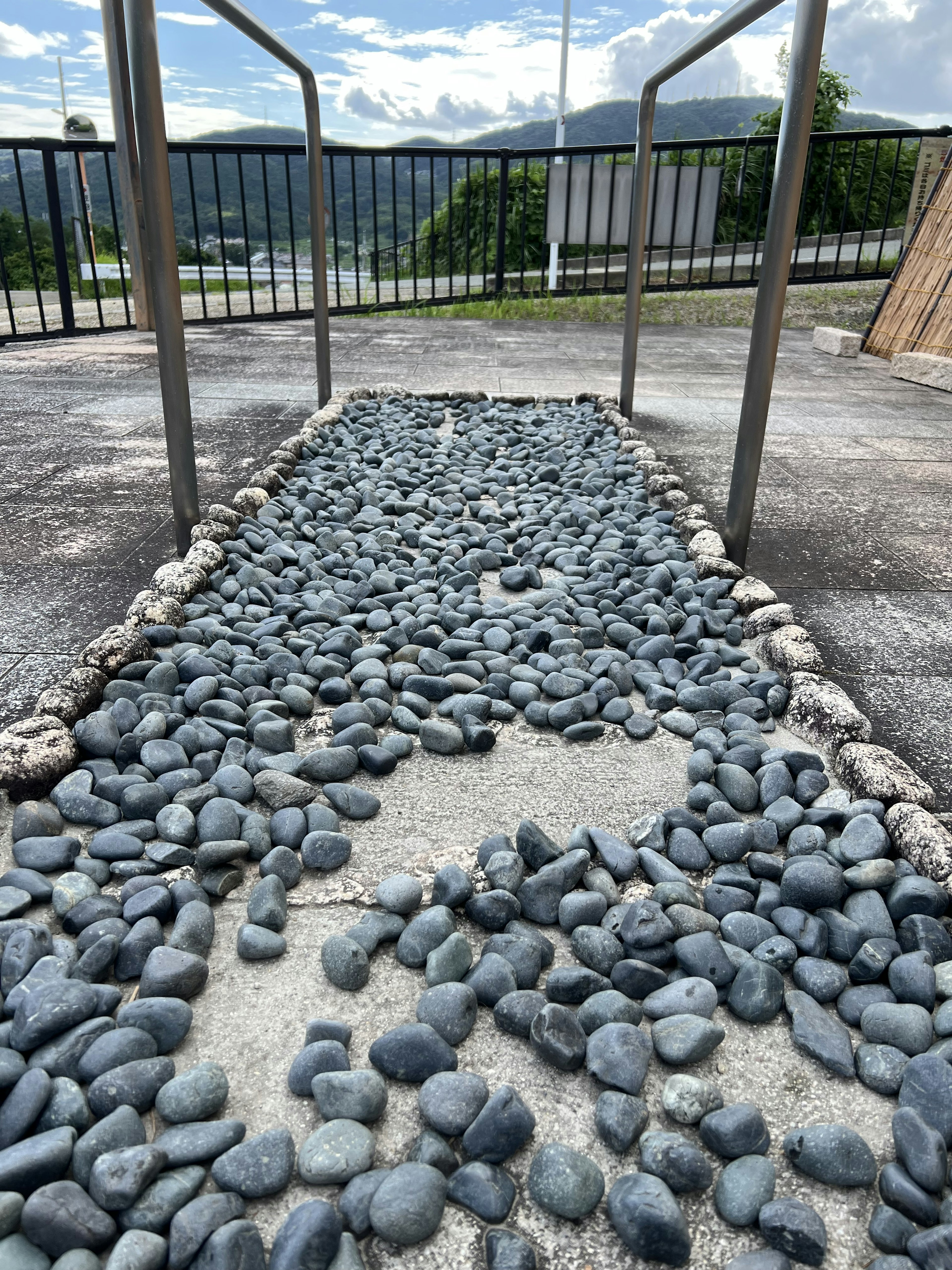 Pathway covered with gray stones flanked by metal railings