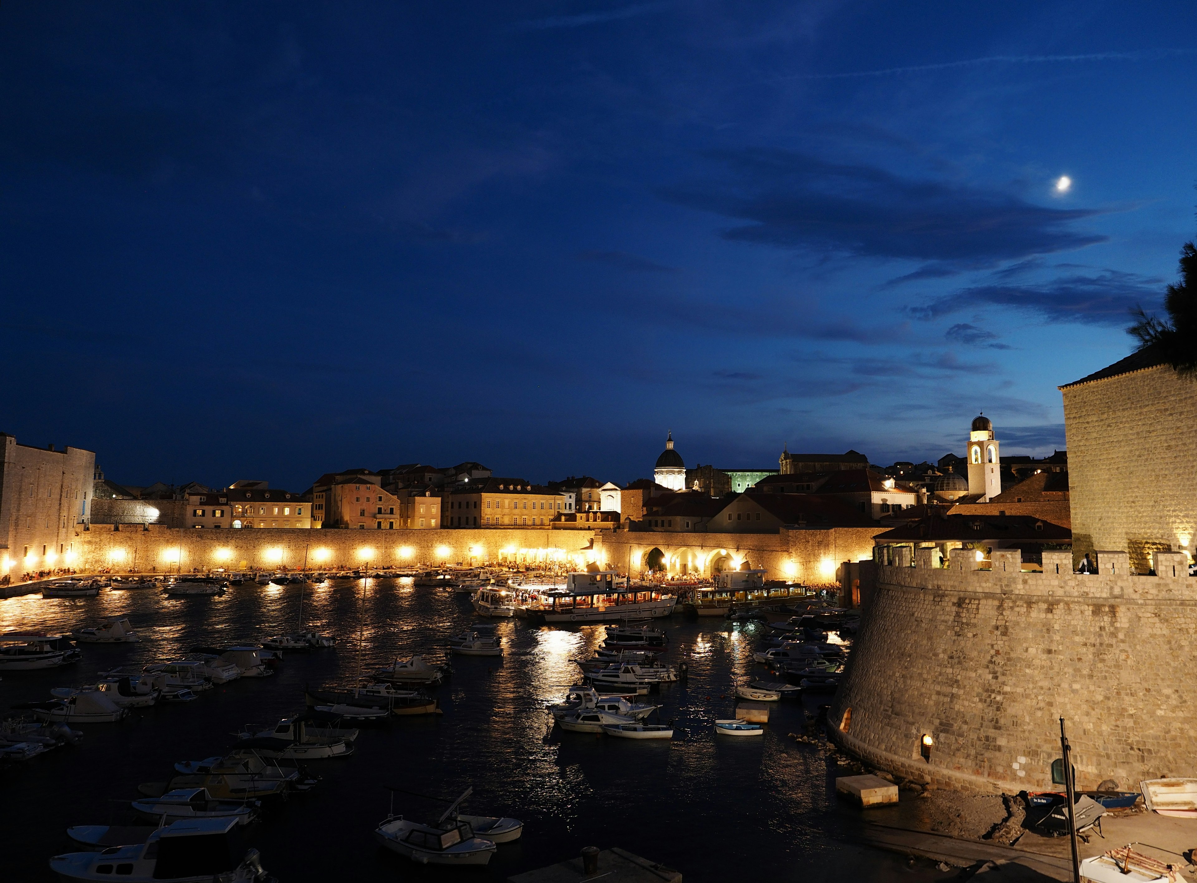 Bella vista notturna di un porto e mura cittadine con acque calme e edifici illuminati