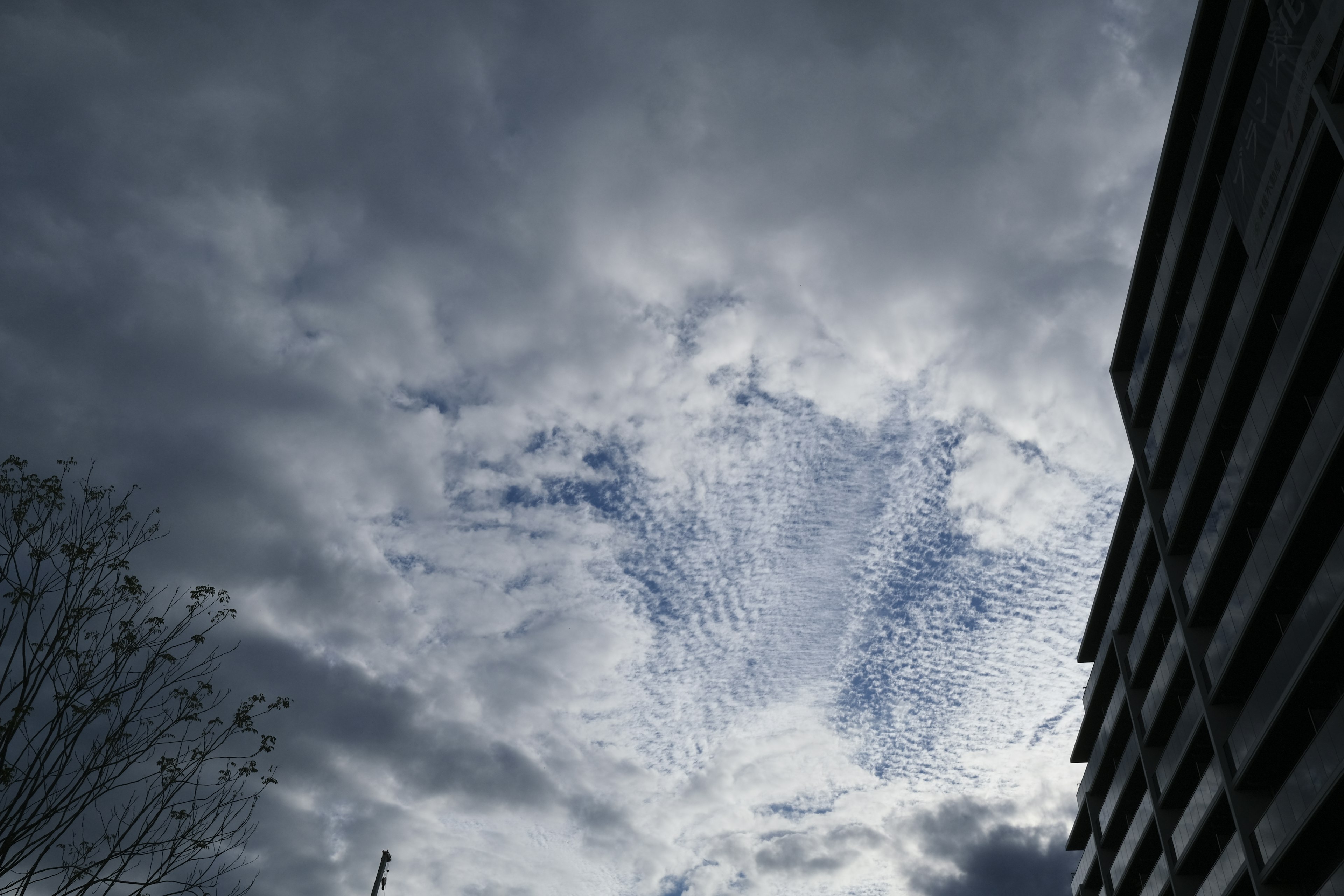 Bewölkter Himmel mit einzigartigen Wolkenmustern und einem Teil eines Gebäudes