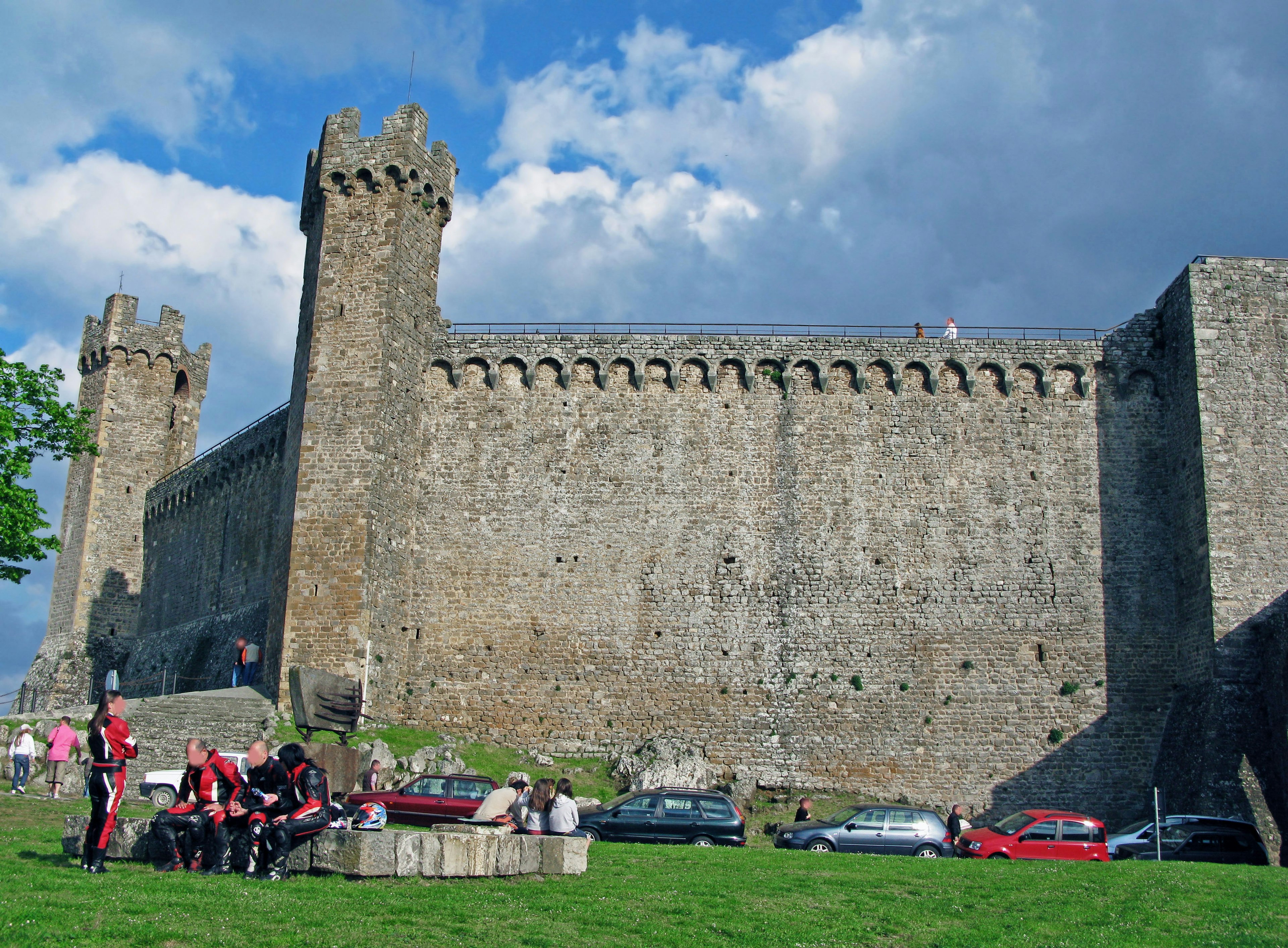 Raggruppamento di persone di fronte a mura e torri di castello medievale