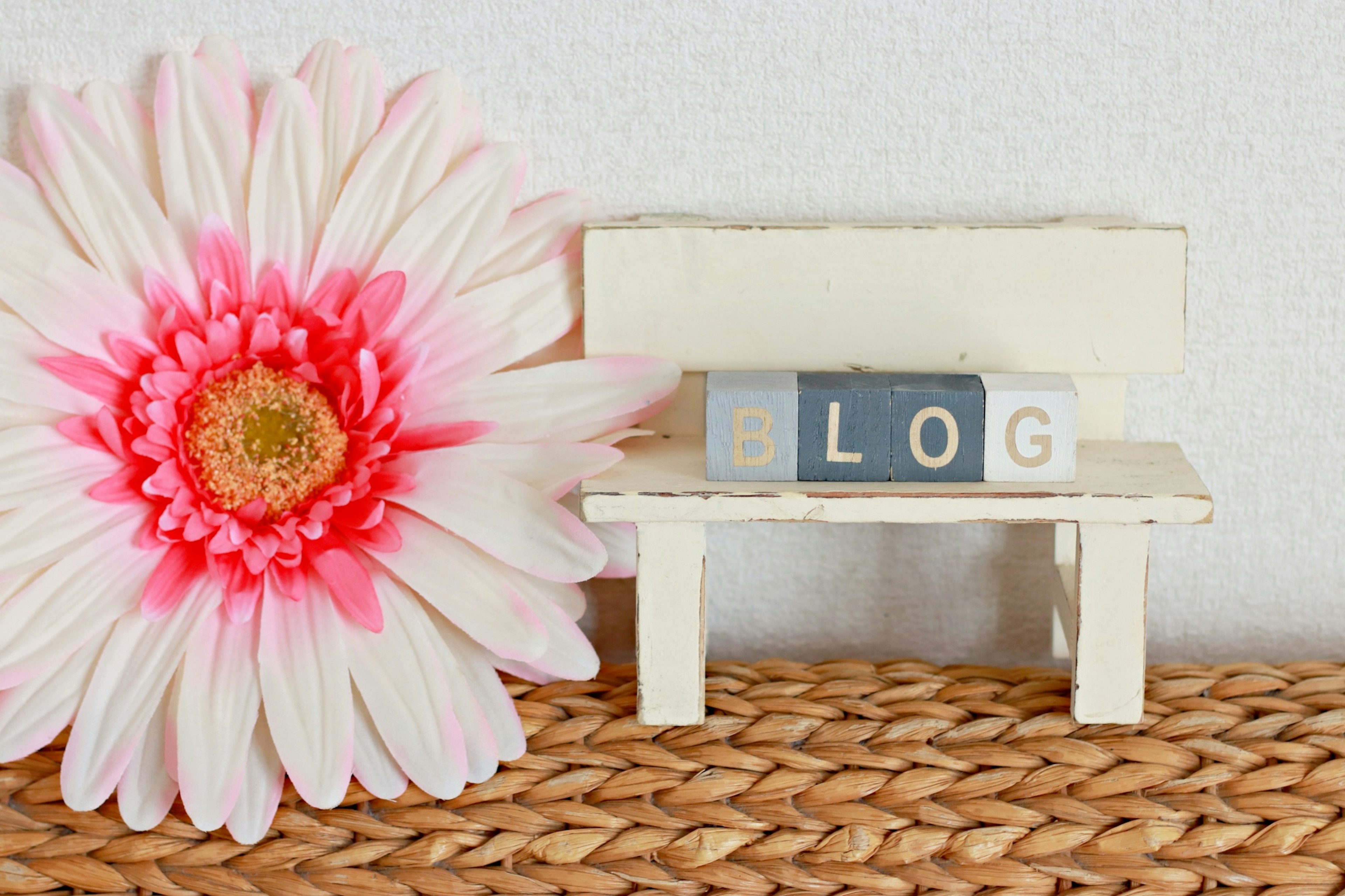 Un banc blanc avec le mot BLOG et une grande fleur rose