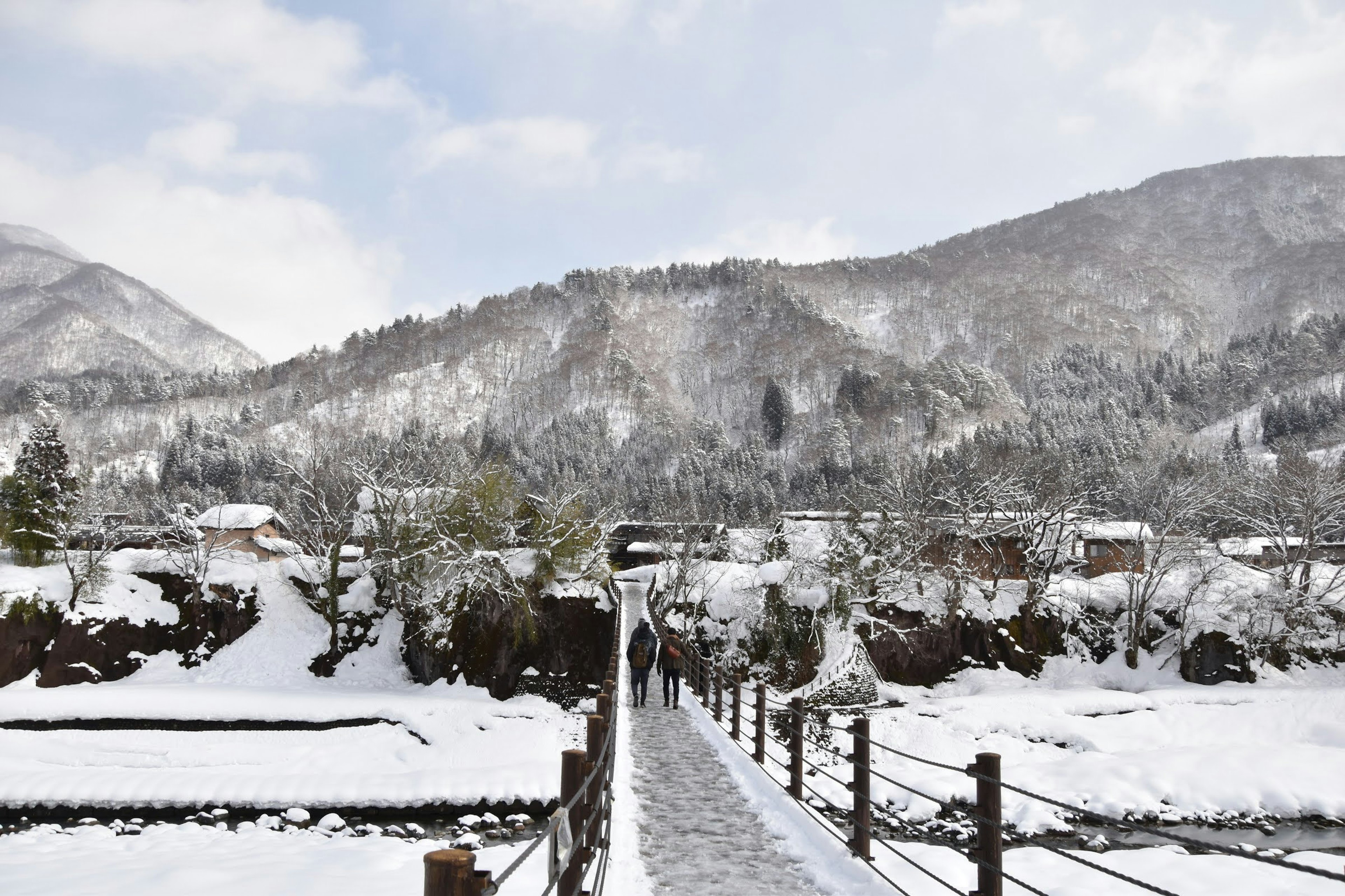 雪に覆われた山々と橋が見える冬の風景