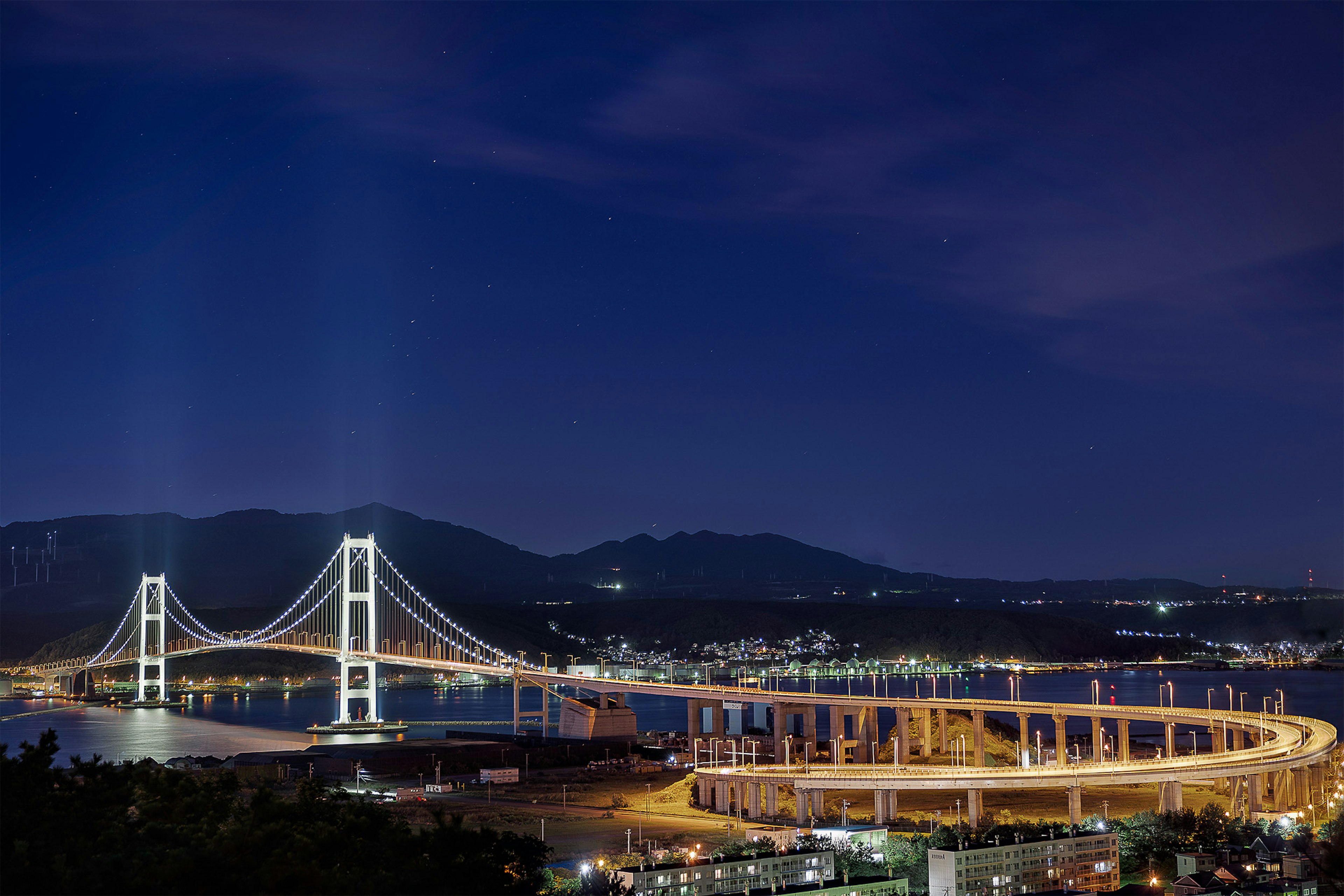 Un grande ponte illuminato con panorama urbano sotto un cielo notturno luminoso