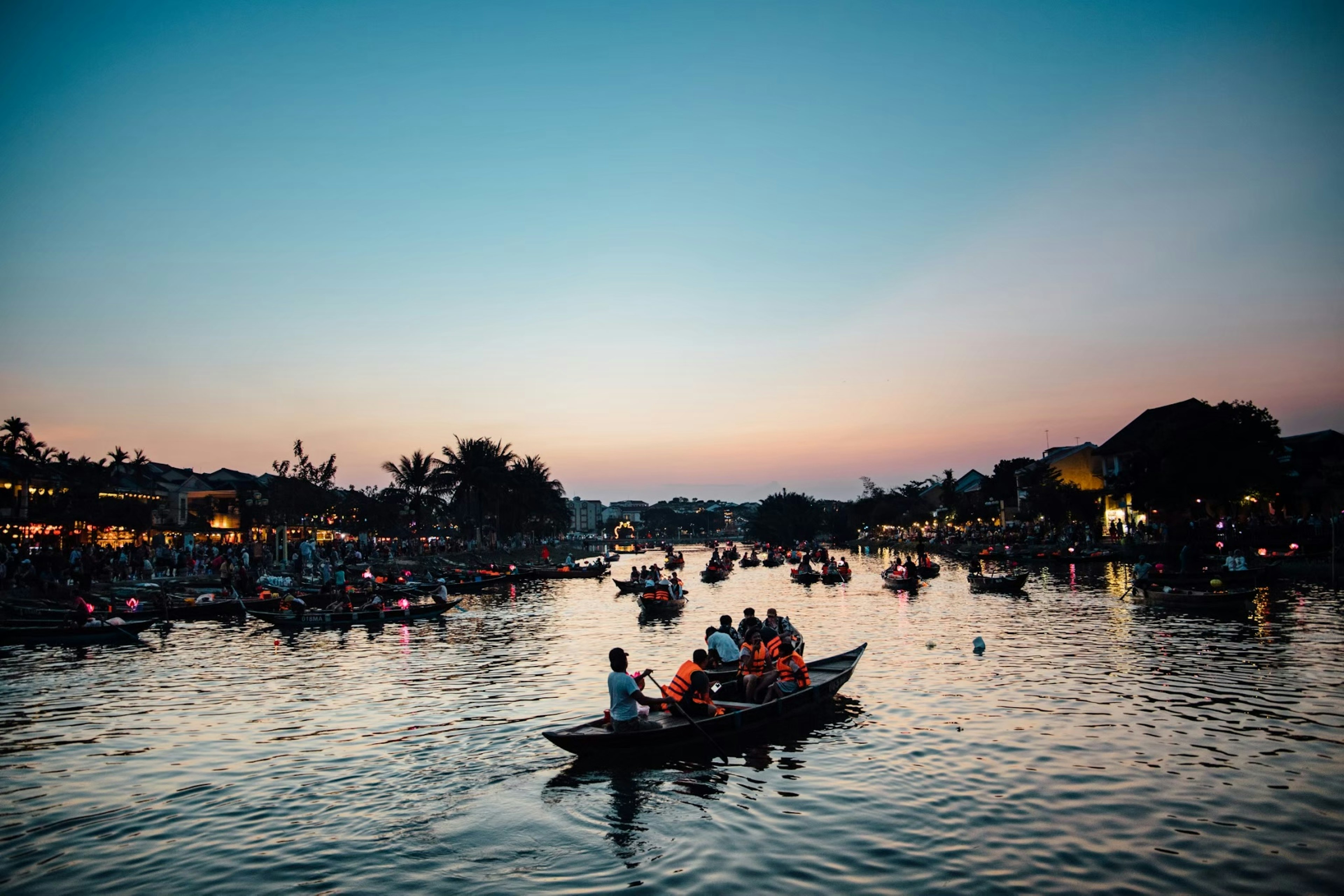 Vue pittoresque de personnes dans des bateaux sur une rivière au crépuscule