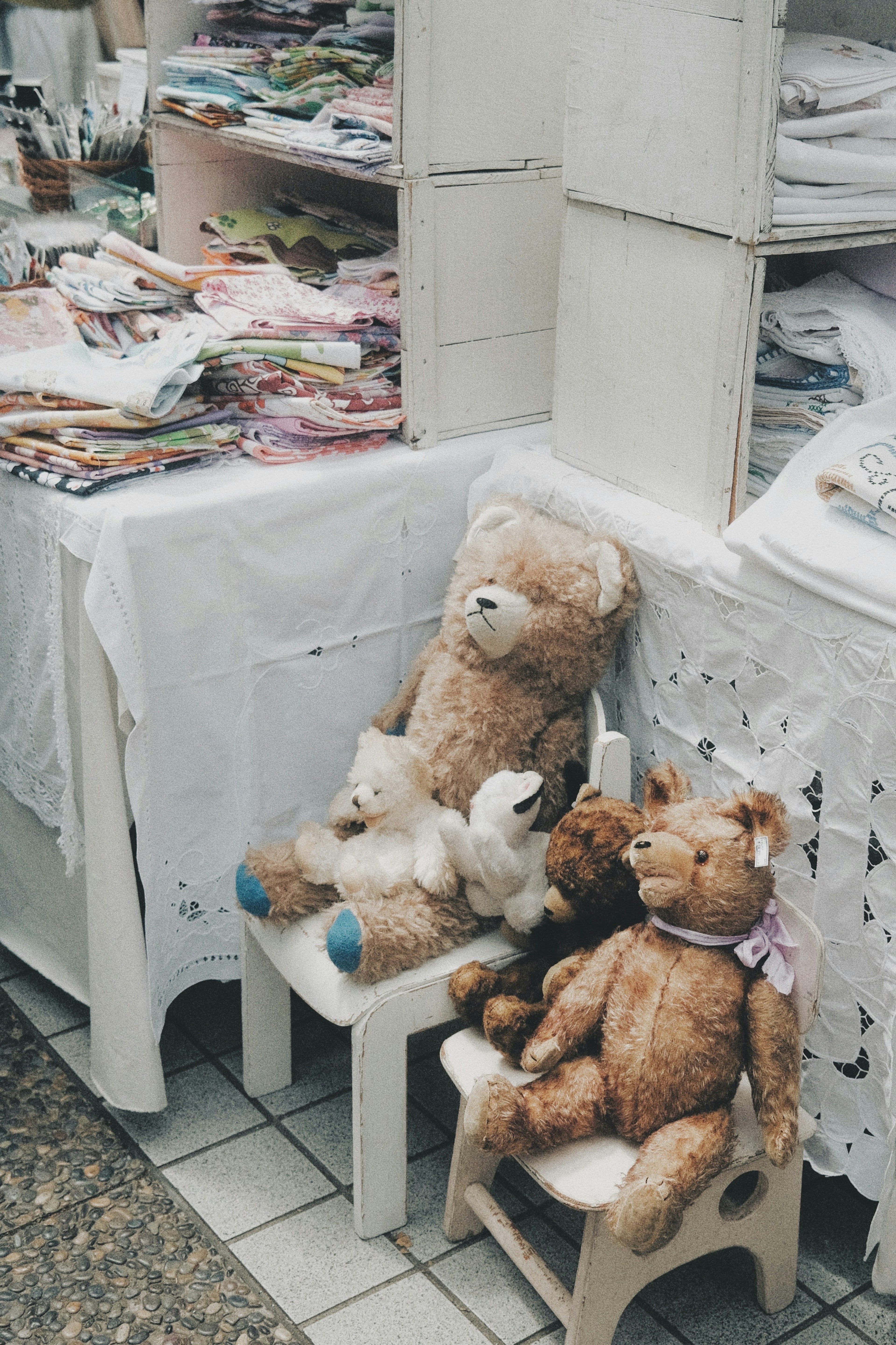 Animales de peluche sentados en sillas con manteles blancos en un mercado