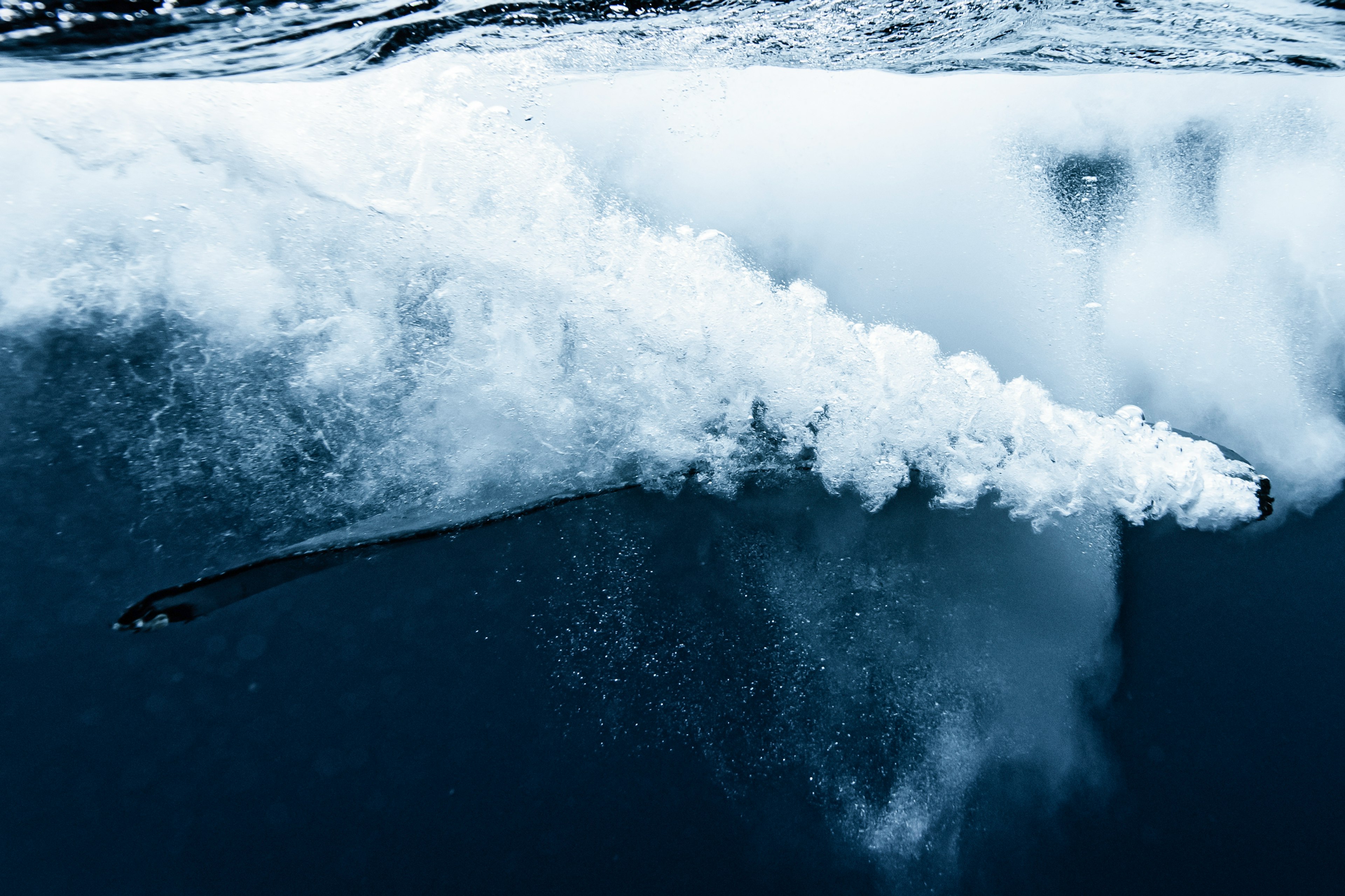 A black object creating bubbles under the water with white foam