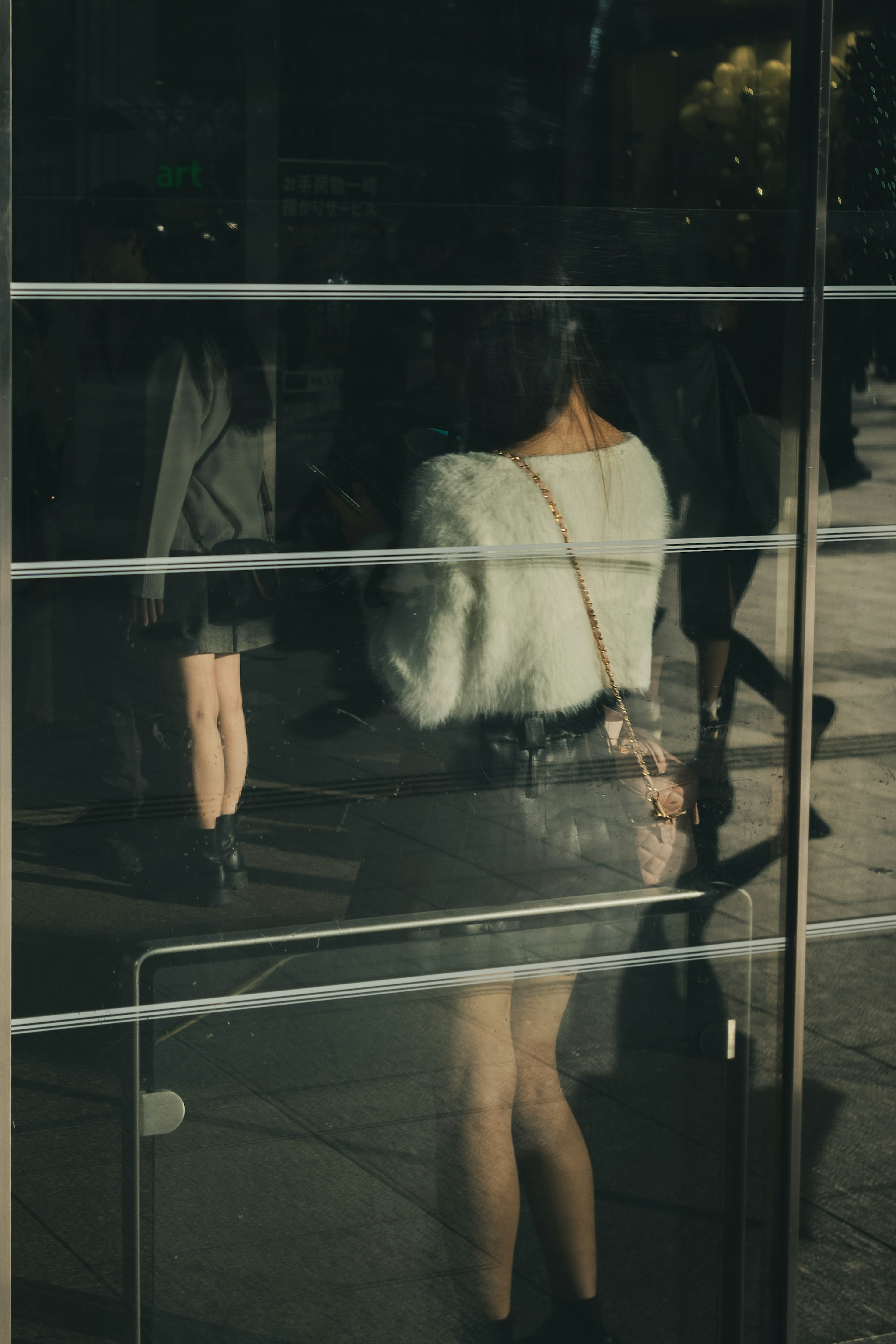 Reflet d'une femme dans une vitre avec des personnes environnantes