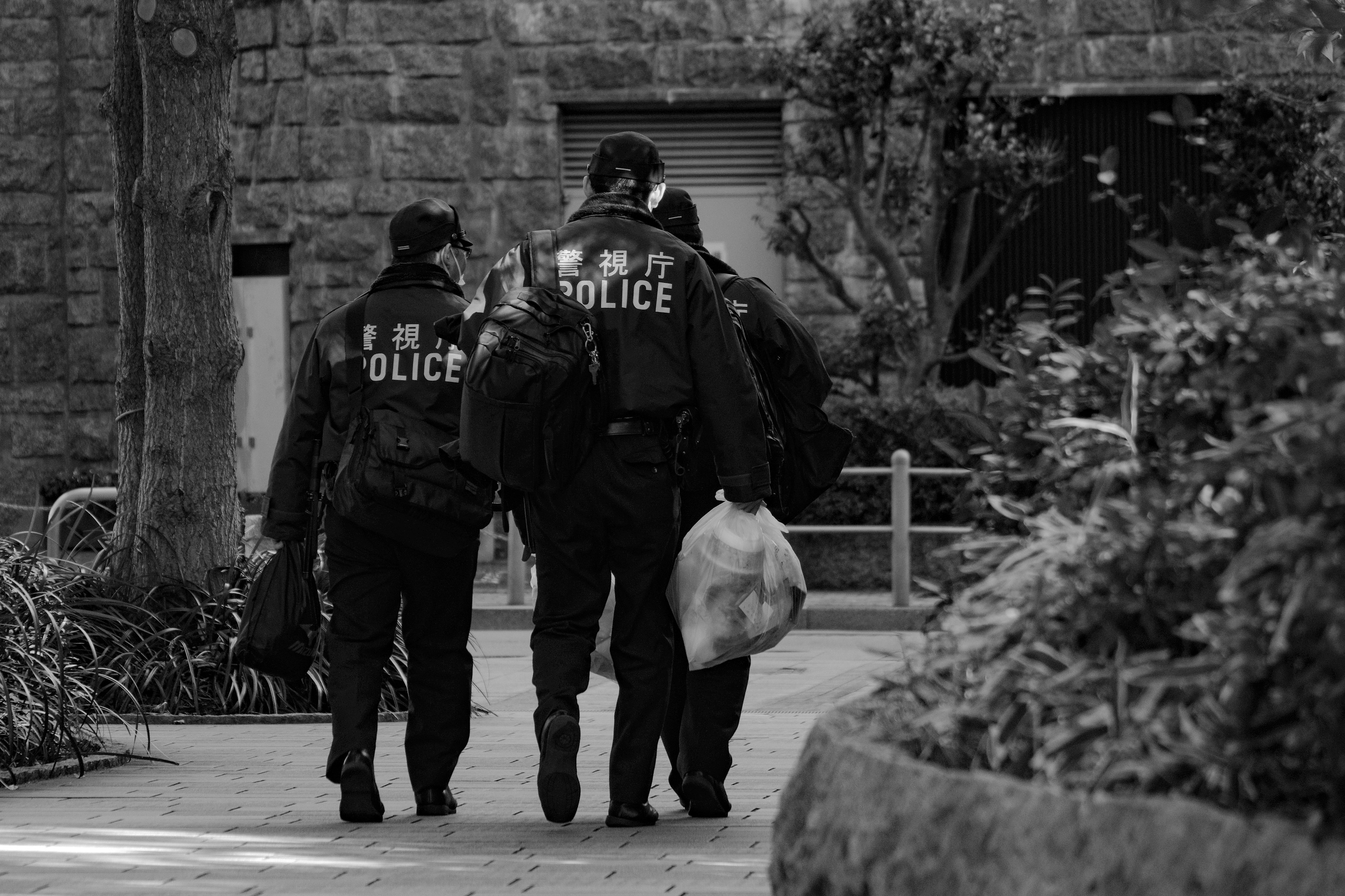 Image en noir et blanc de policiers marchant dans un parc