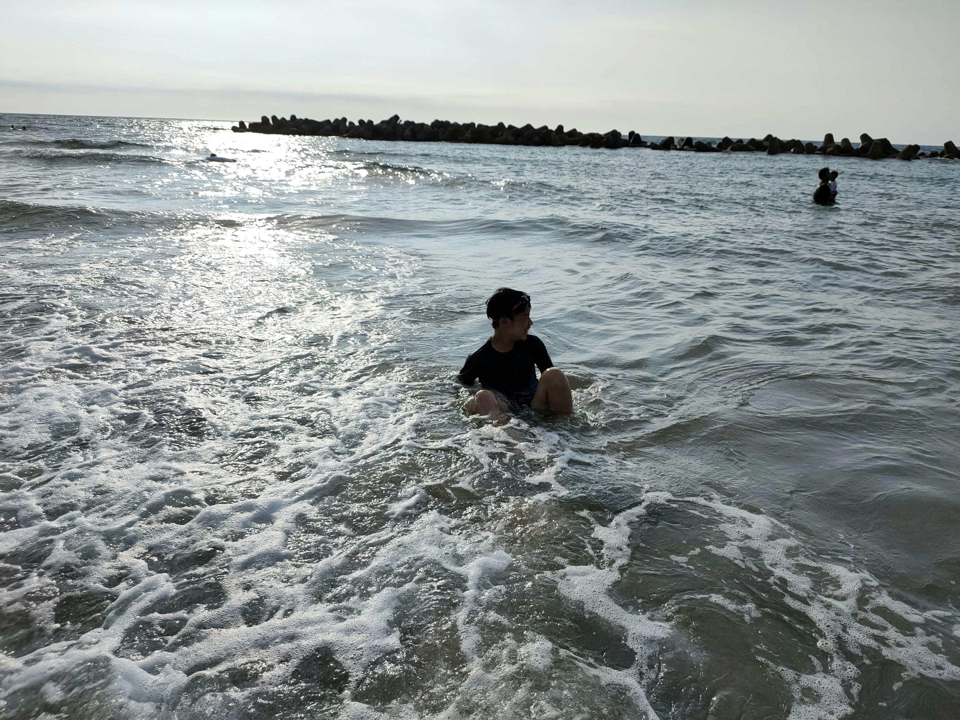 Kind spielt im Meer mit Wellen, die um ihn spritzen