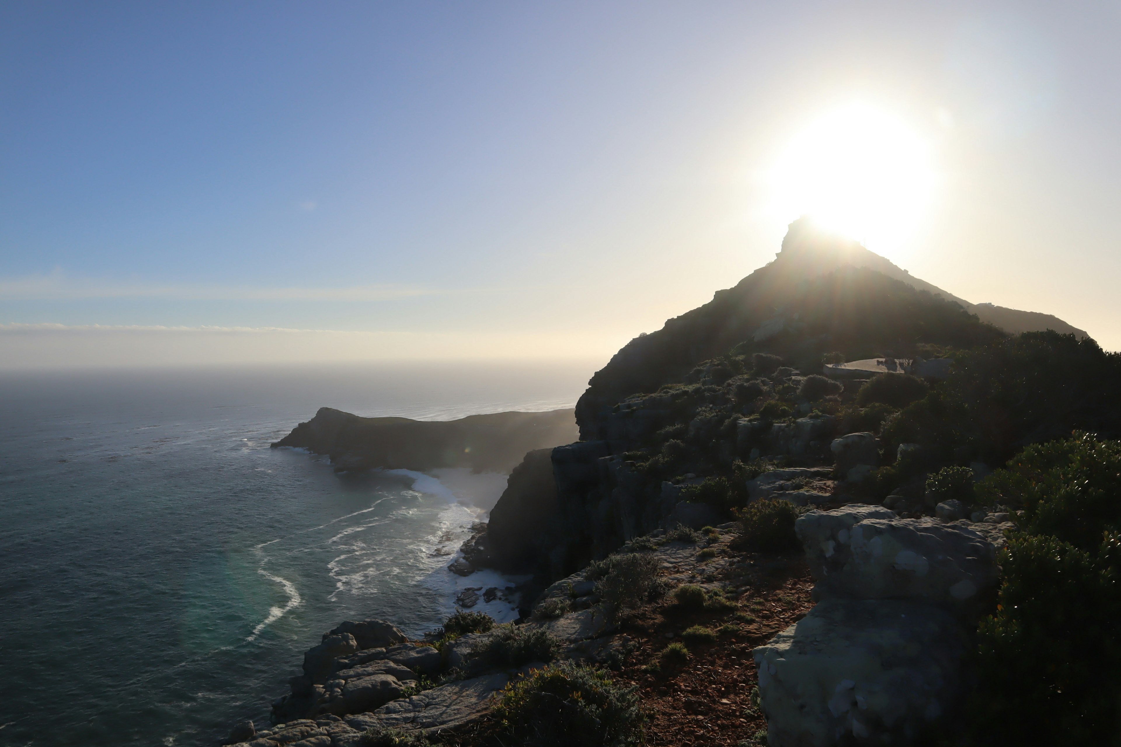 Vista escénica de la costa y silueta de montaña al atardecer