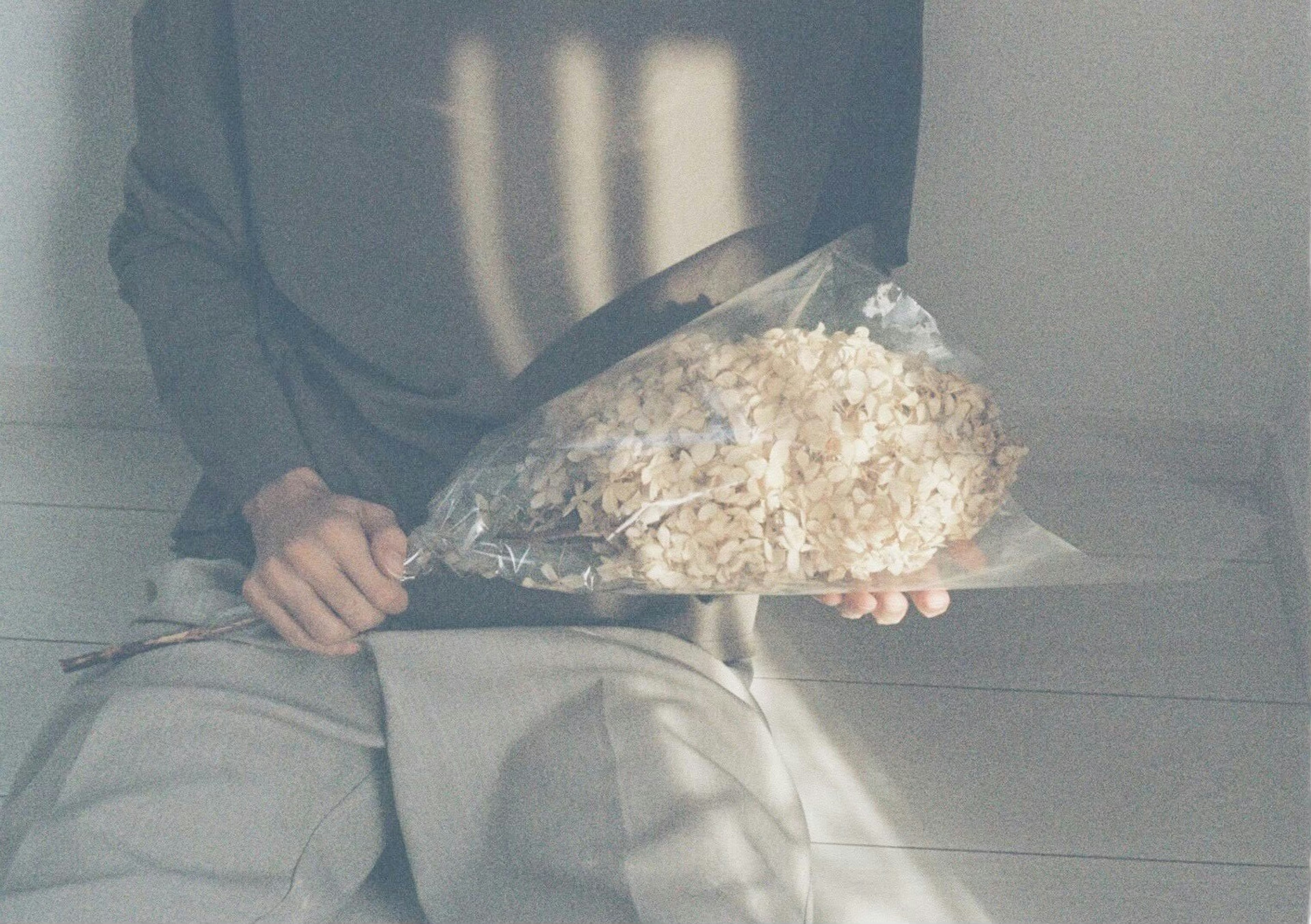 Person holding a bouquet with soft light and shadows