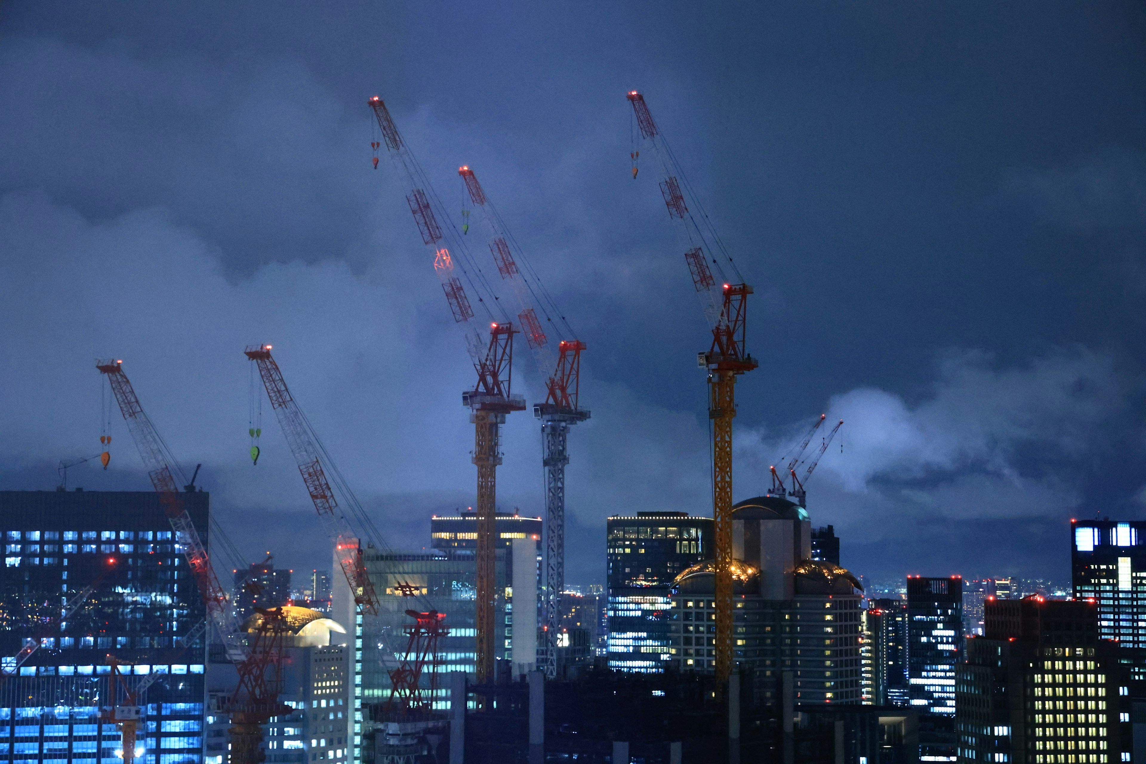 Siluet derek dan gedung pencakar langit dalam pemandangan kota malam