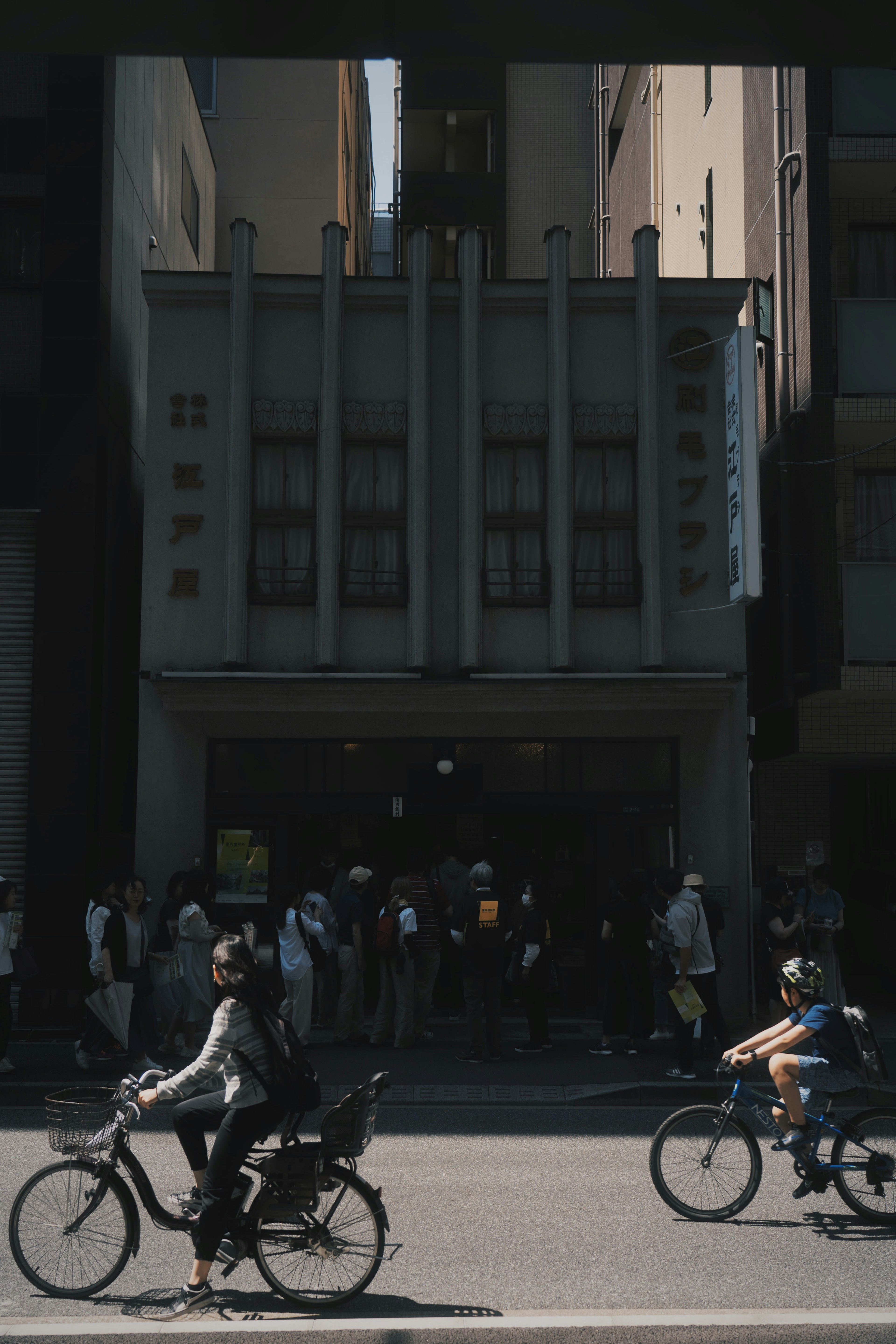 City scene featuring people on bicycles and an old building