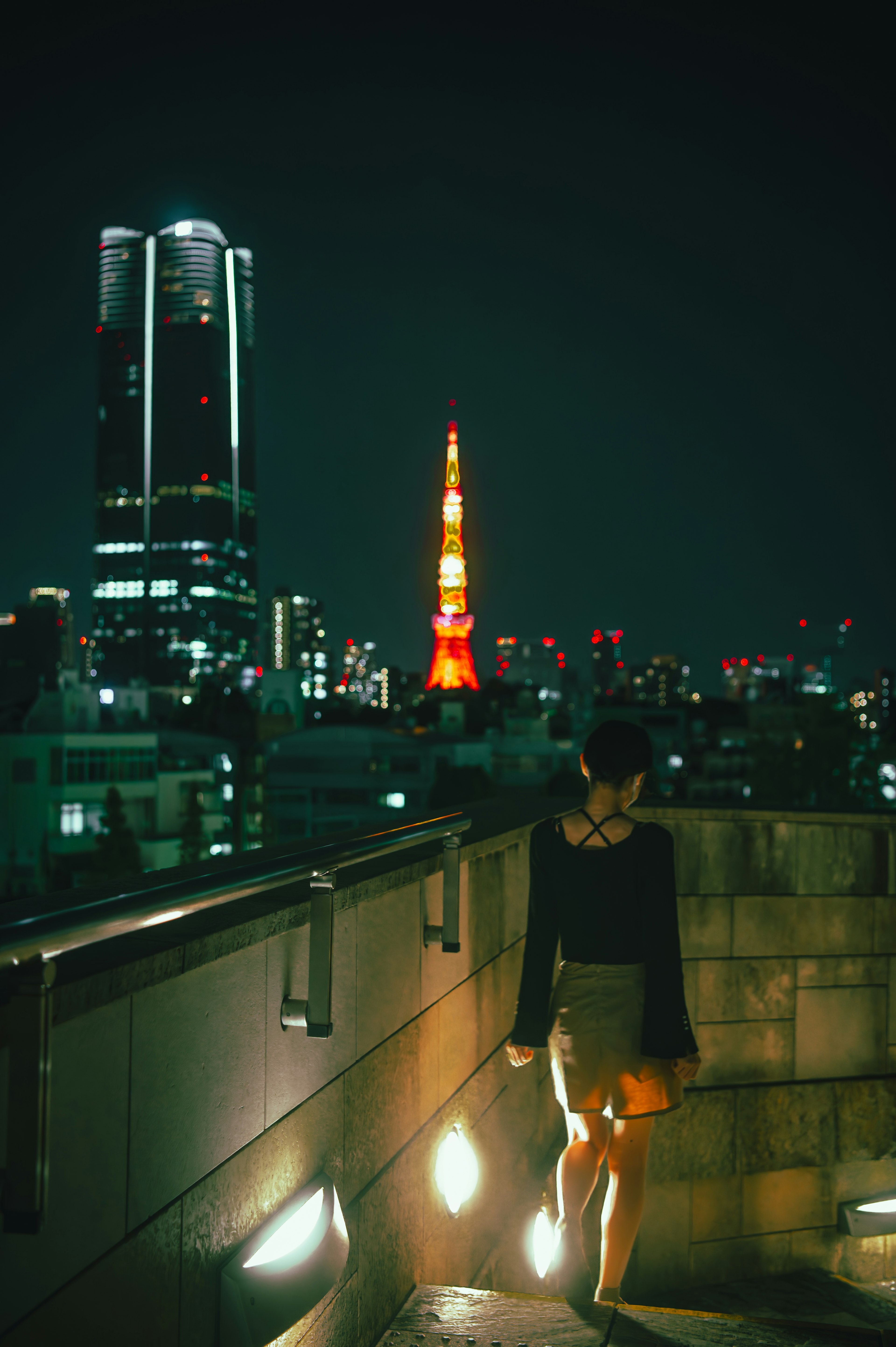 A woman walking in Tokyo at night with Tokyo Tower in the background