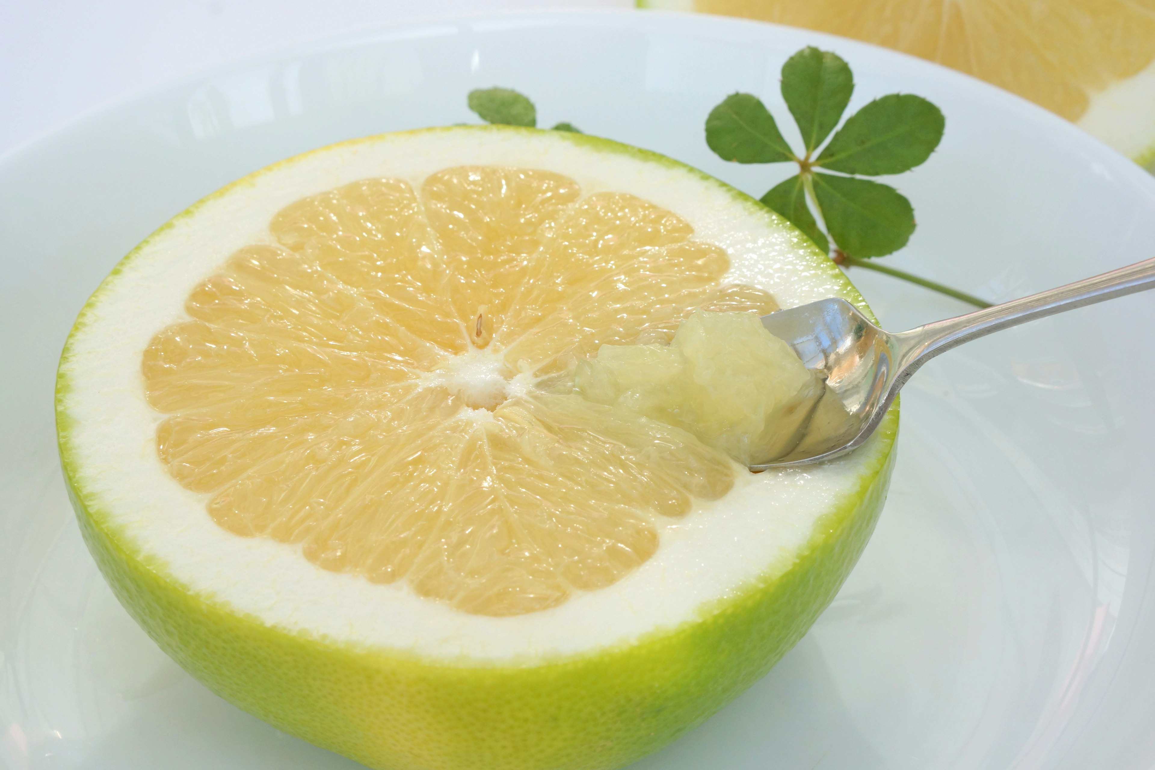 Half of a green-skinned lemon with a spoon scooping out the pulp