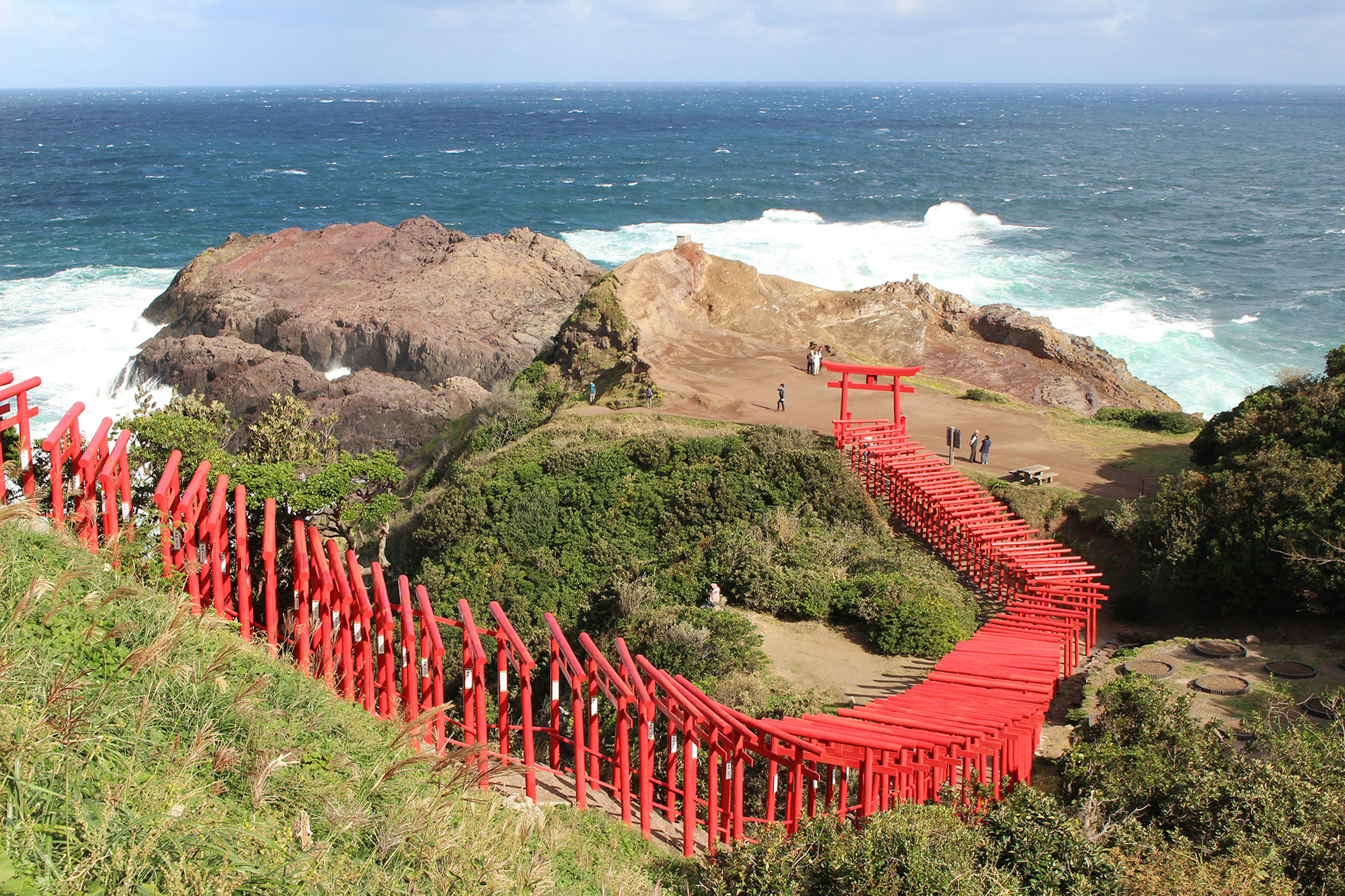 Un chemin sinueux de torii rouges menant à l'océan