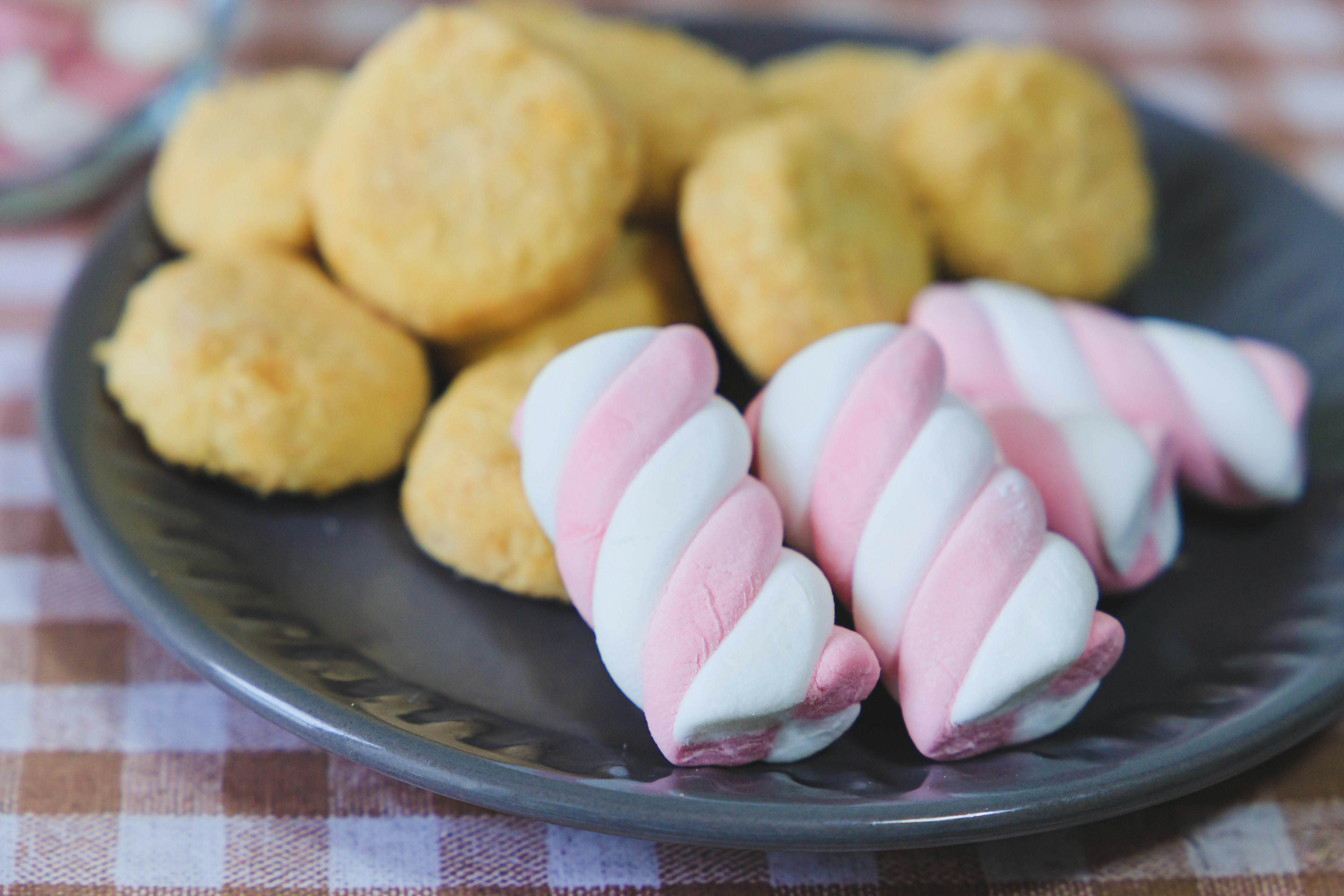 Ein Teller mit gelben Keksen und rosa-weißen Marshmallows