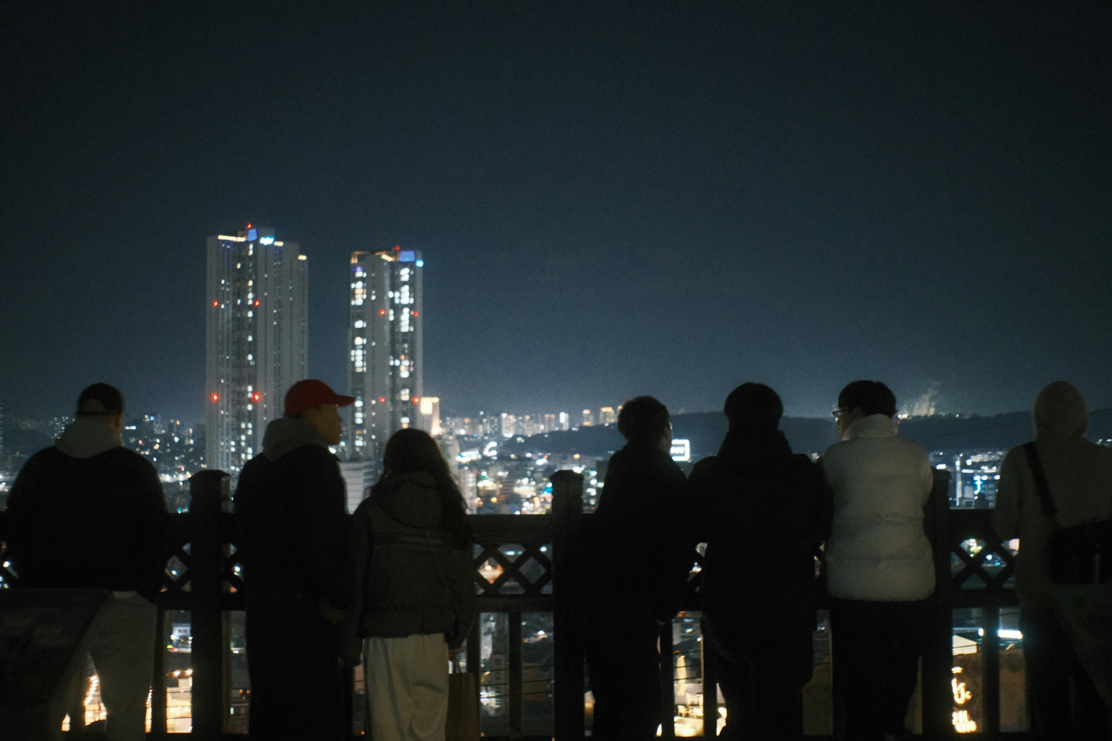 夜景を楽しむ人々が立っている様子と高層ビルが見える