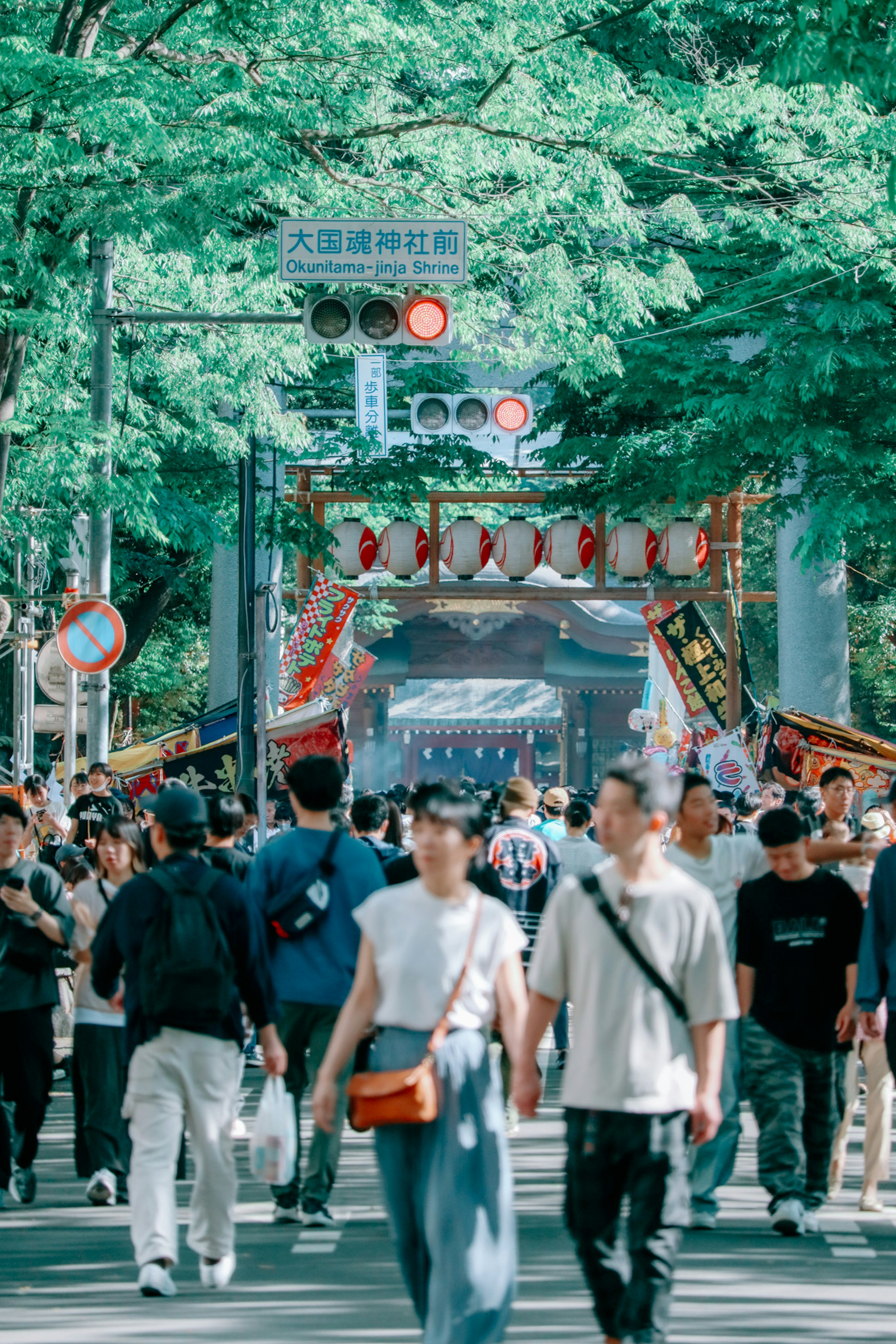 緑の木々に囲まれた通りを歩く人々の群れと祭りの装飾