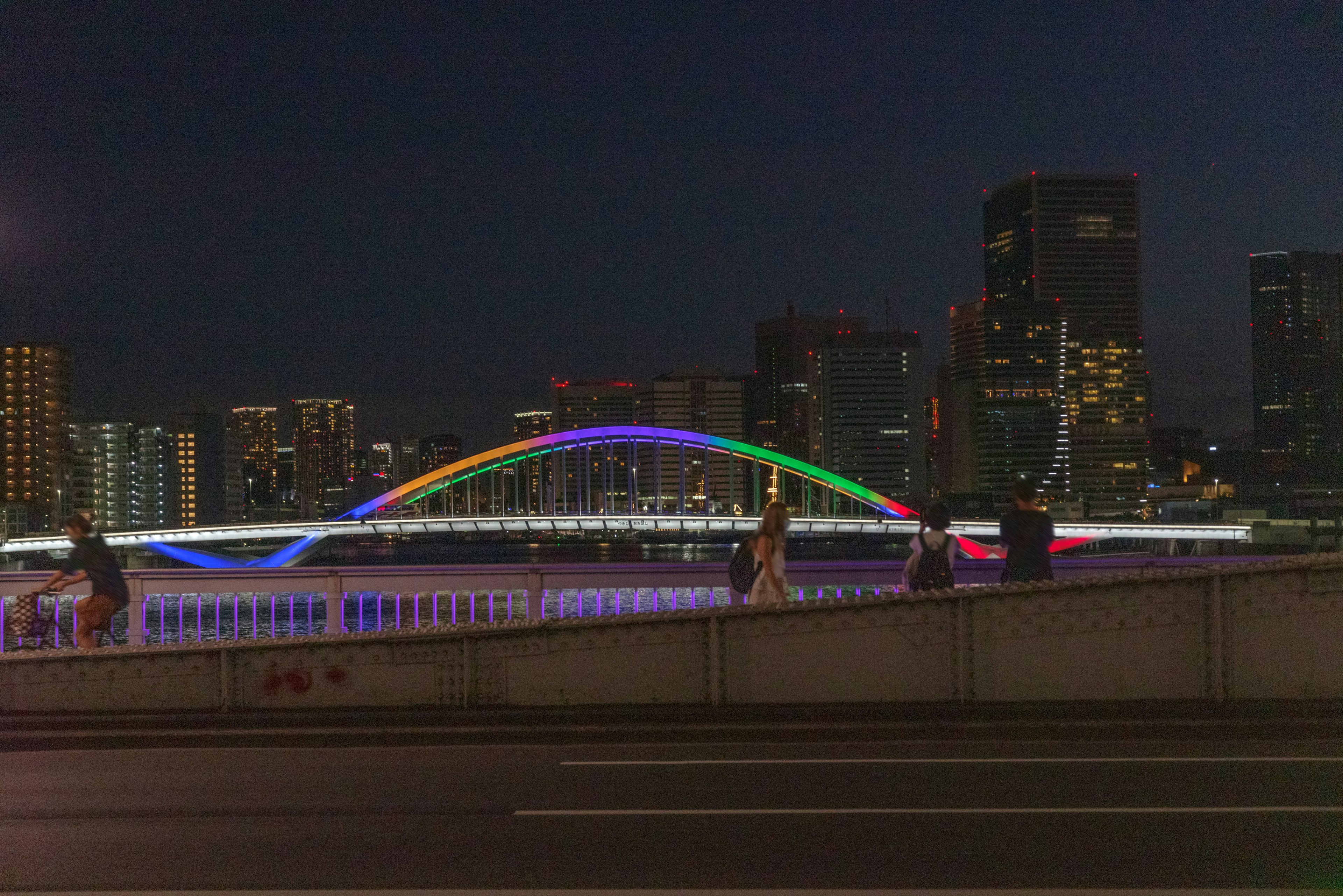 夜间照亮的彩虹拱桥与城市天际线背景